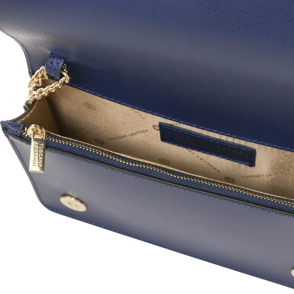 Close-up of a navy blue leather clutch bag showing the interior zippered compartment with a beige patterned lining and gold-tone hardware.