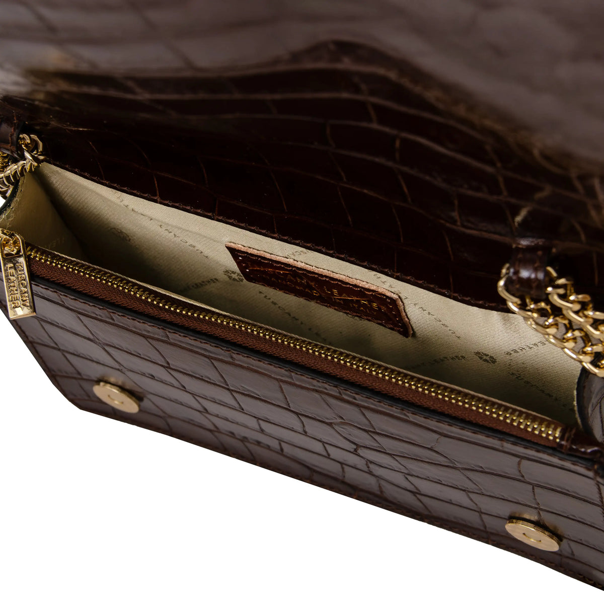 Close-up of a coffee crocodile-embossed leather handbag showing the interior with a gold zippered compartment, gold chain strap, and beige lining. 