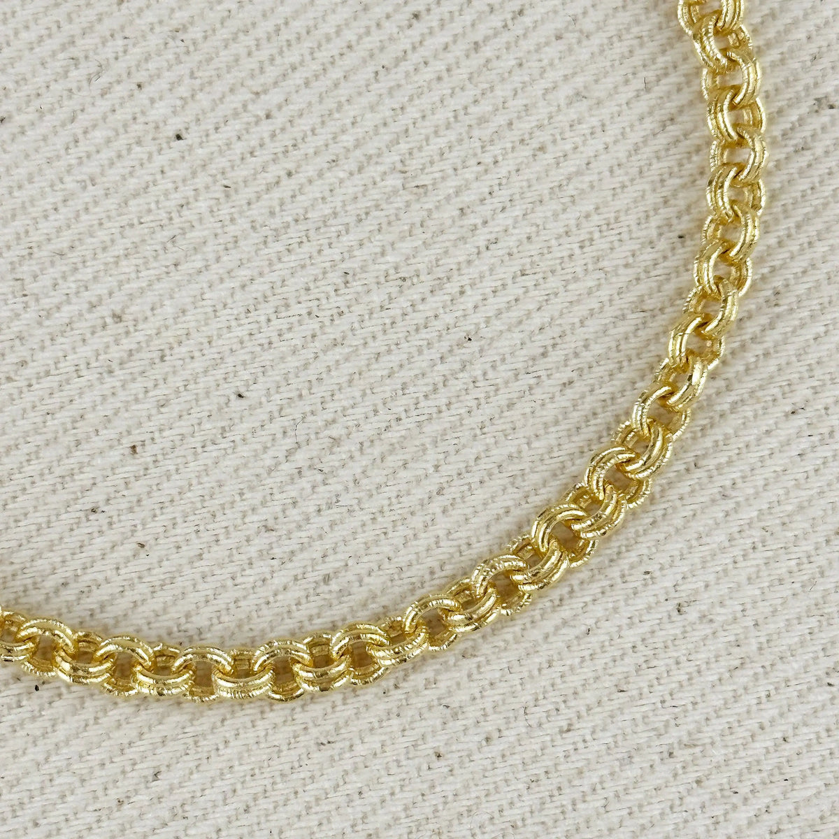 Close up of gold chain link necklace on a natural woven textured background