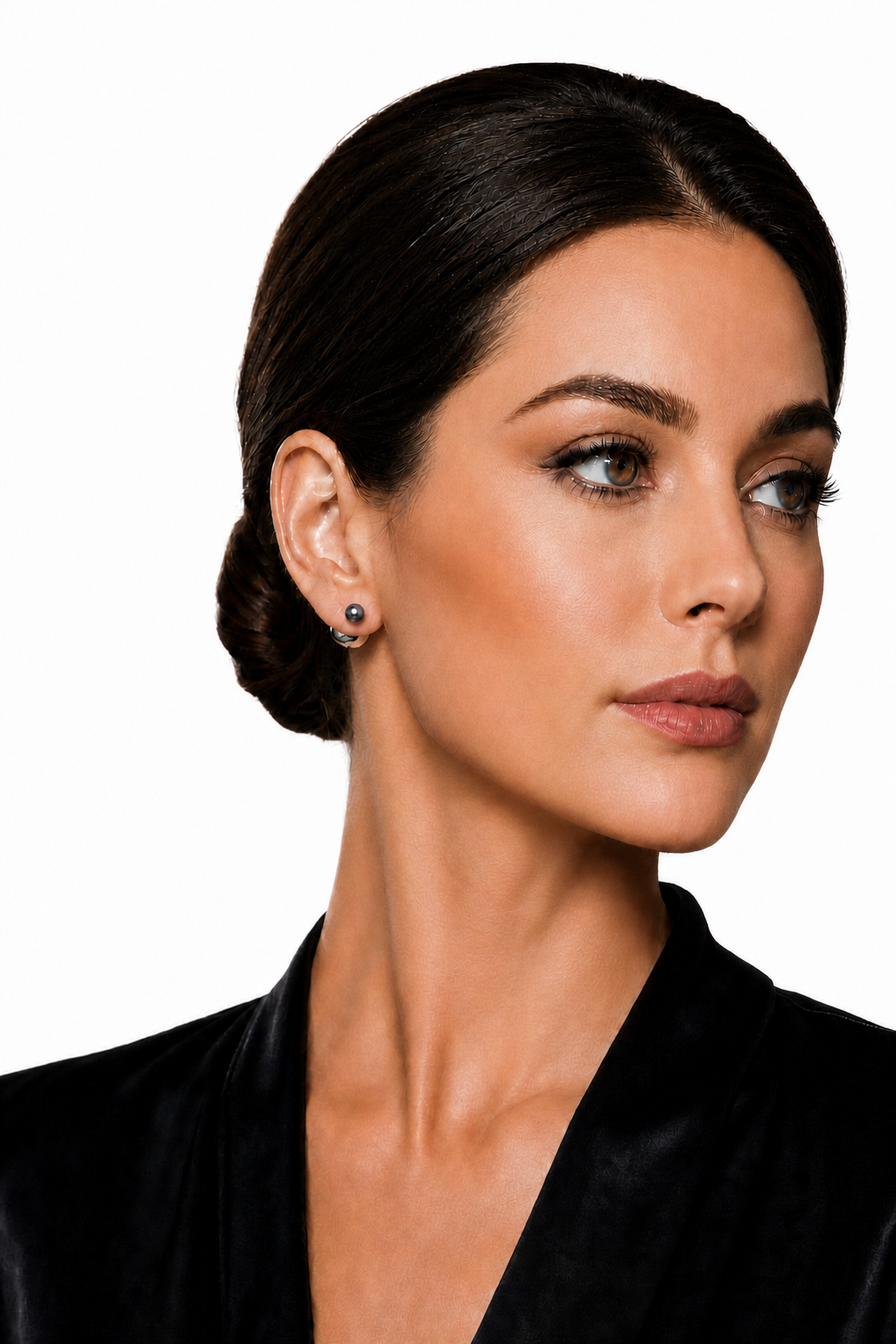 A close-up portrait of a woman with dark hair in an updo, wearing a black velvet top and a small black pear earring against a plain white background.
