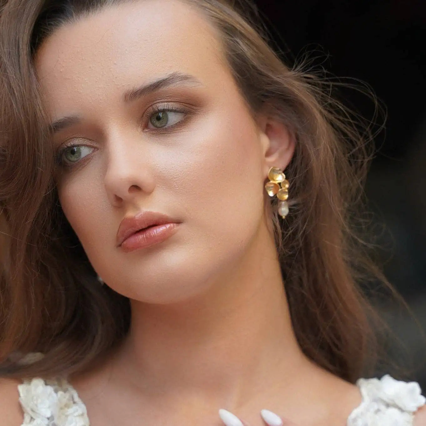 A  woman with her light brown hair down wearing the Amalfi Golden Petal Drop Earrings
