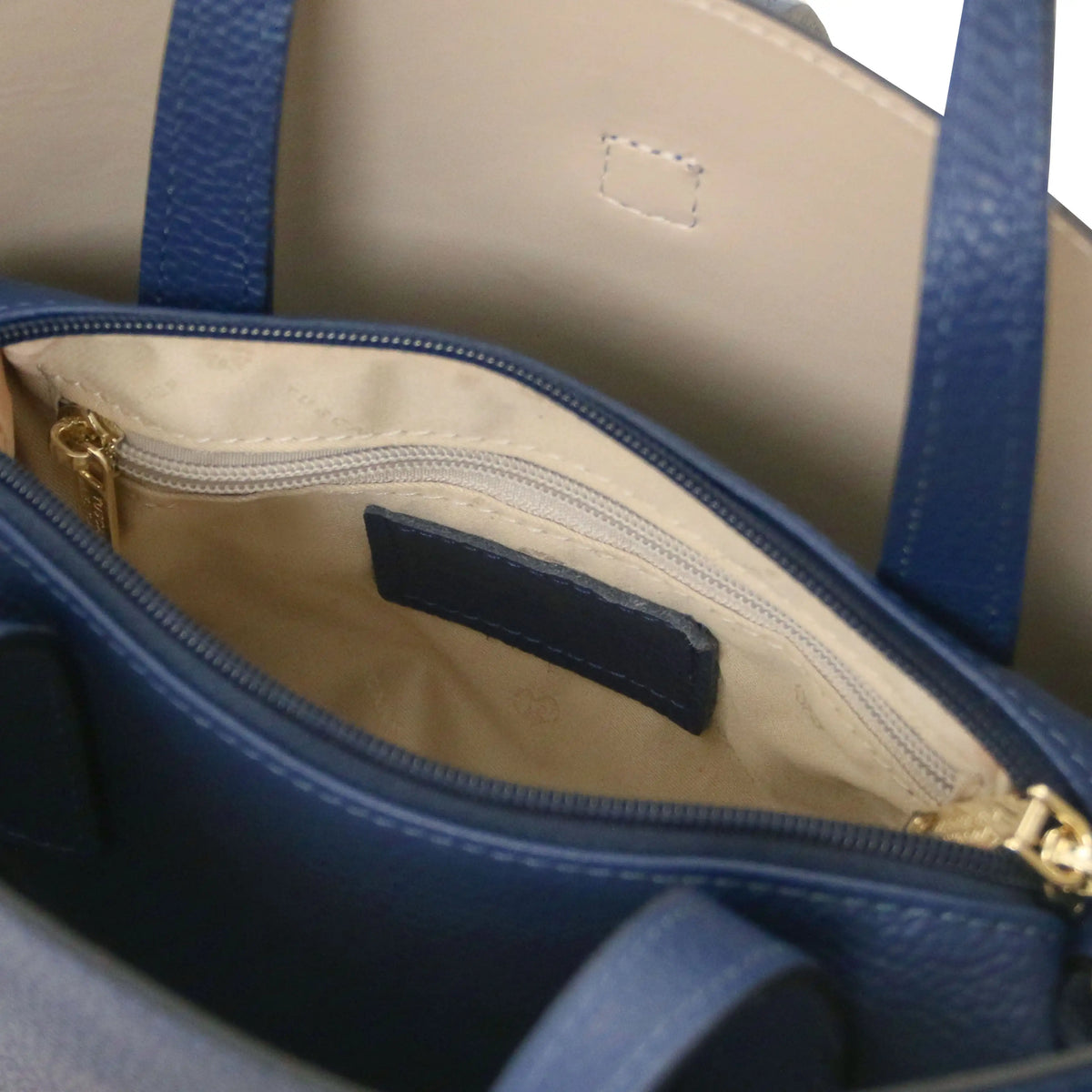 Interior beige lining view Agatha Leather Handbag in dark blue showing un zipped central compartment