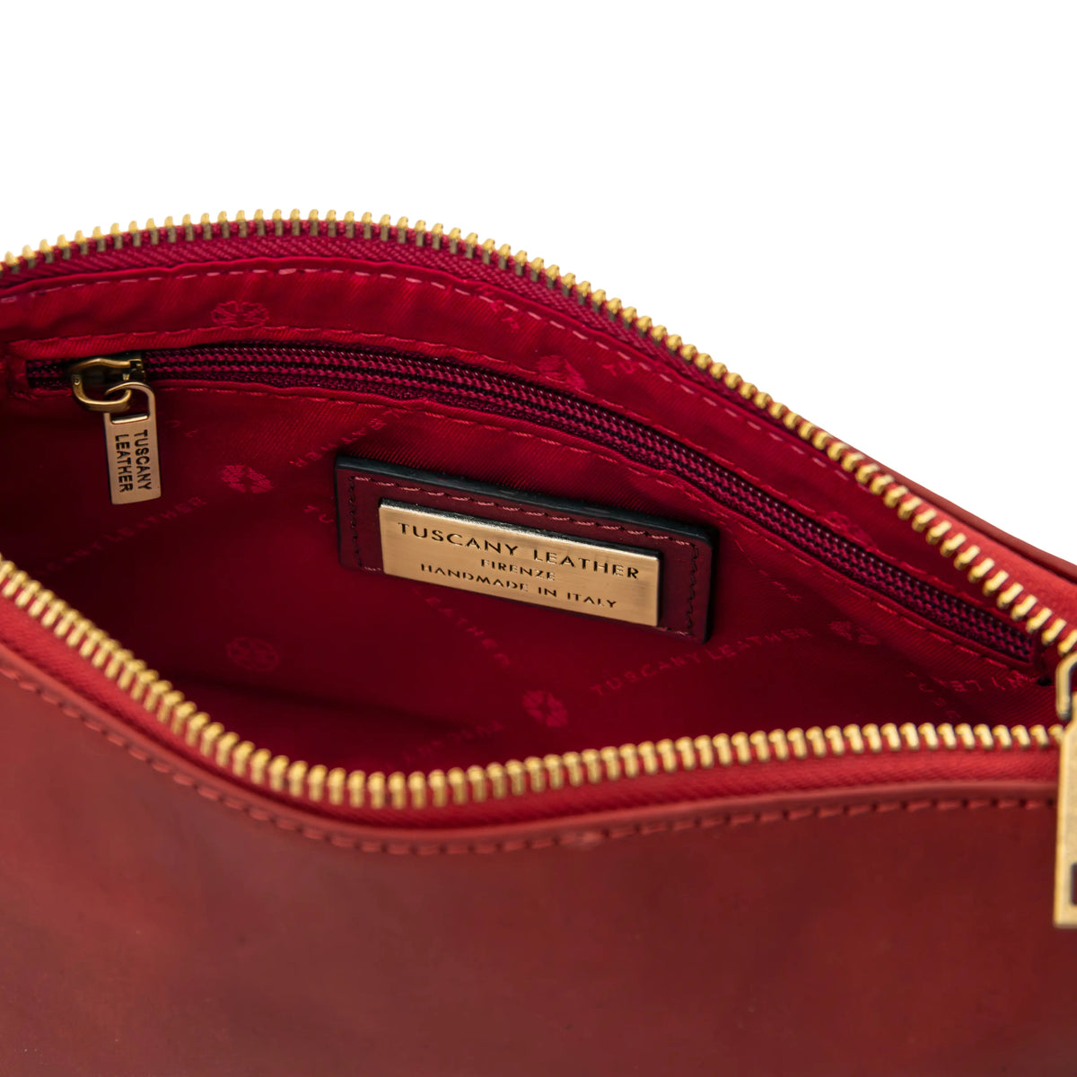 Red leather bag with gold zipper, red lining and 'Tuscany Leather' label on a white background