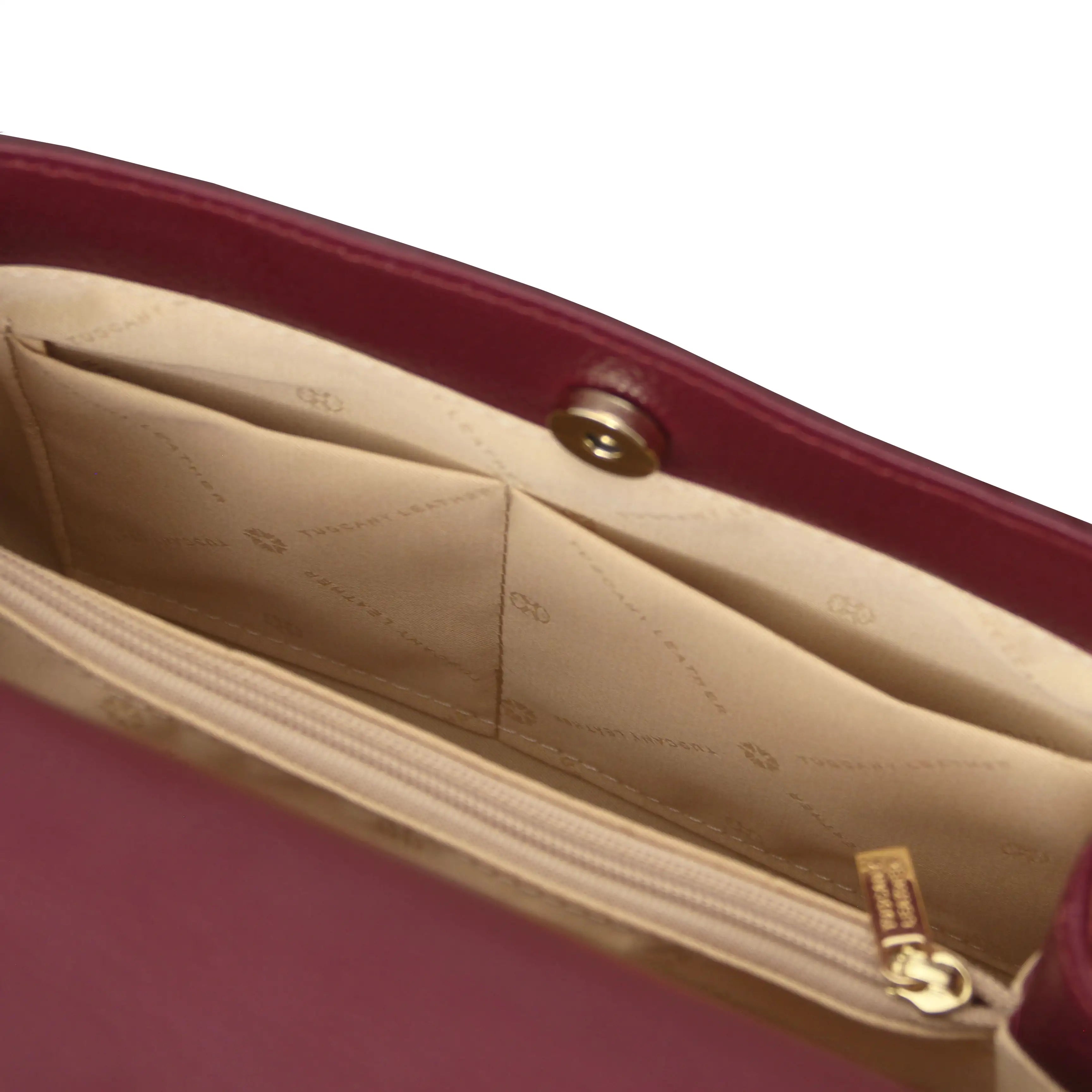 Close-up of a bordeaux handbag with beige interior on a white background