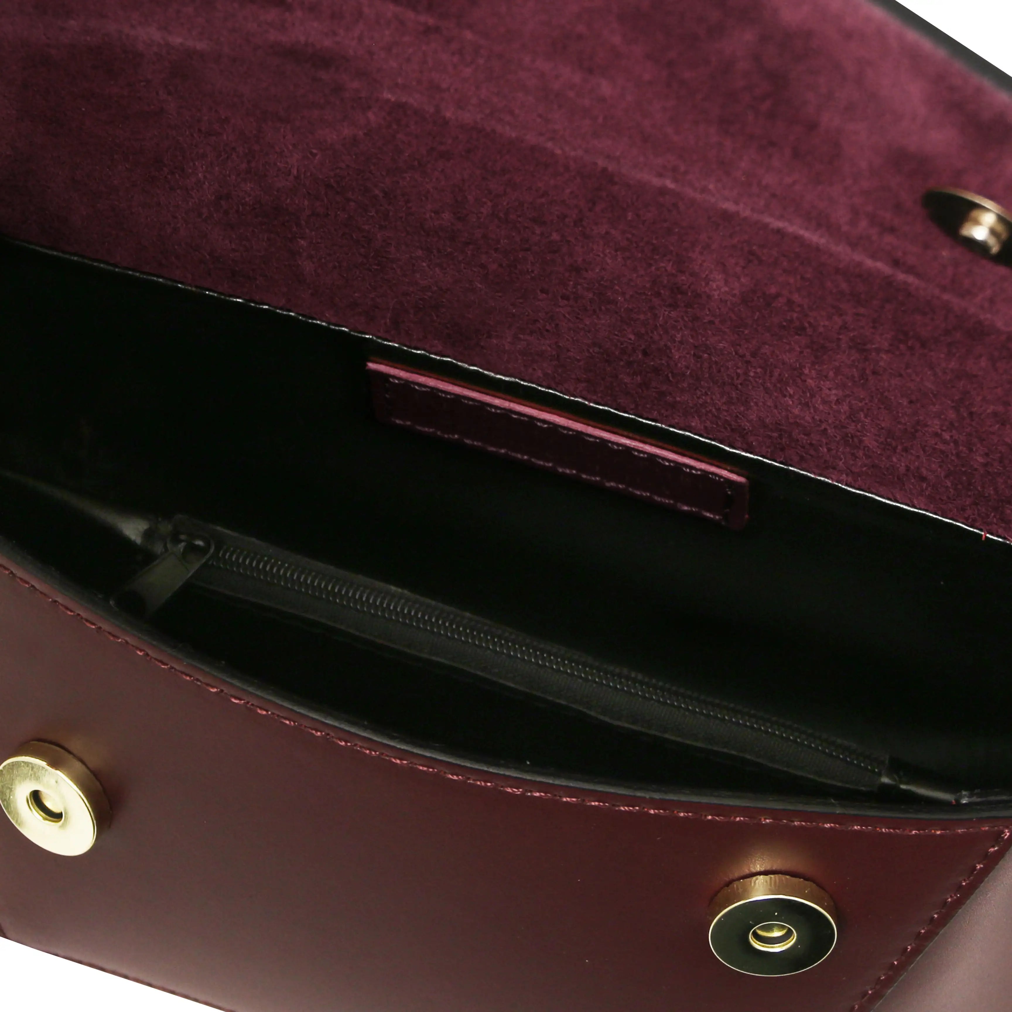 Close-up of a bordeaux handbag with black lining and gold hardware on a white background