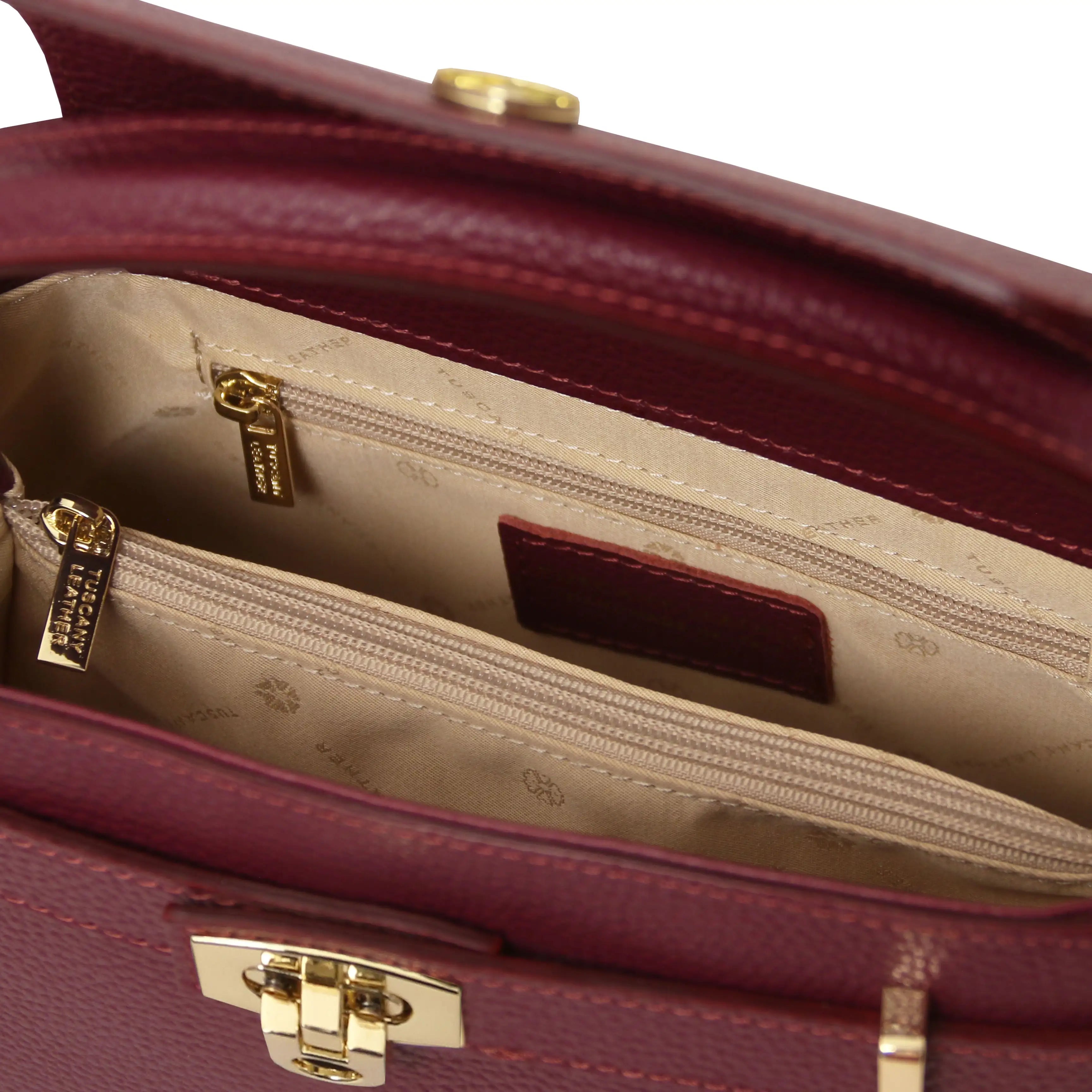 Close-up of a burgundy handbag with gold hardware, showing the beige interior.
