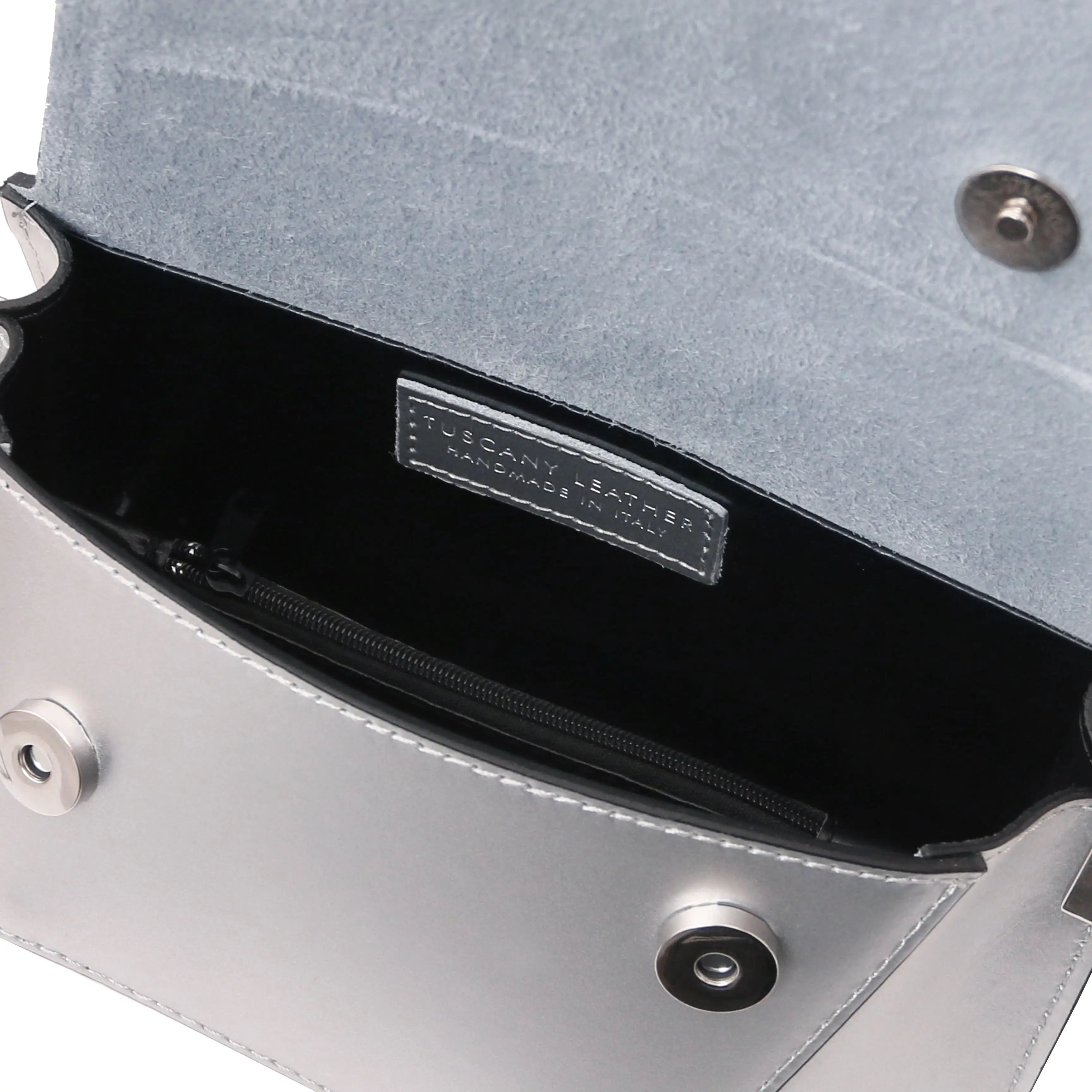 Close-up of an open silver metallic handbag showing a black interior, zippered compartment, and a silver-tone brand label that reads TUSCANY LEATHER