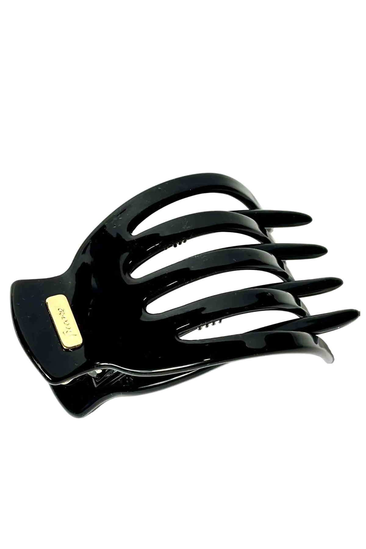 A glossy black hair claw clip with a small gold-tone brand plaque on the side, photographed on a clean white background.