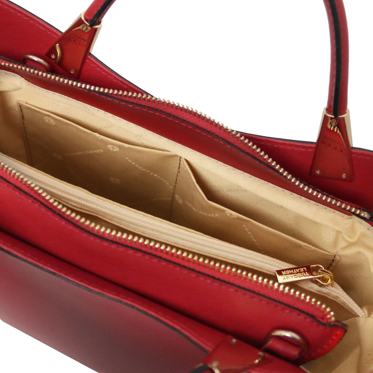 Close-up of a red leather handbag showing the interior compartments, beige lining, and gold-tone zipper hardware on a white background.