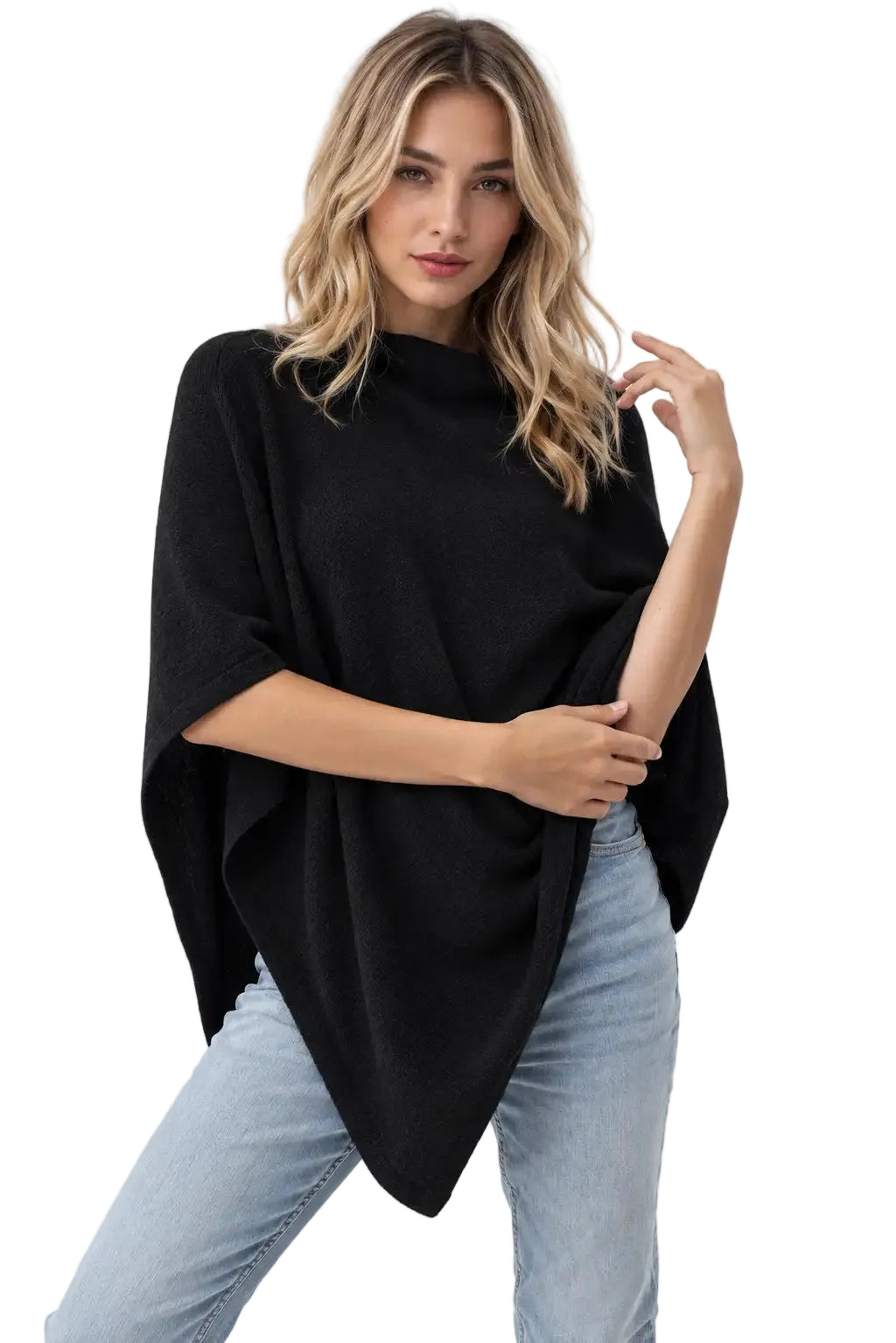 A woman modeling a black draped poncho cashmere top with light blue jeans against a plain white studio background.