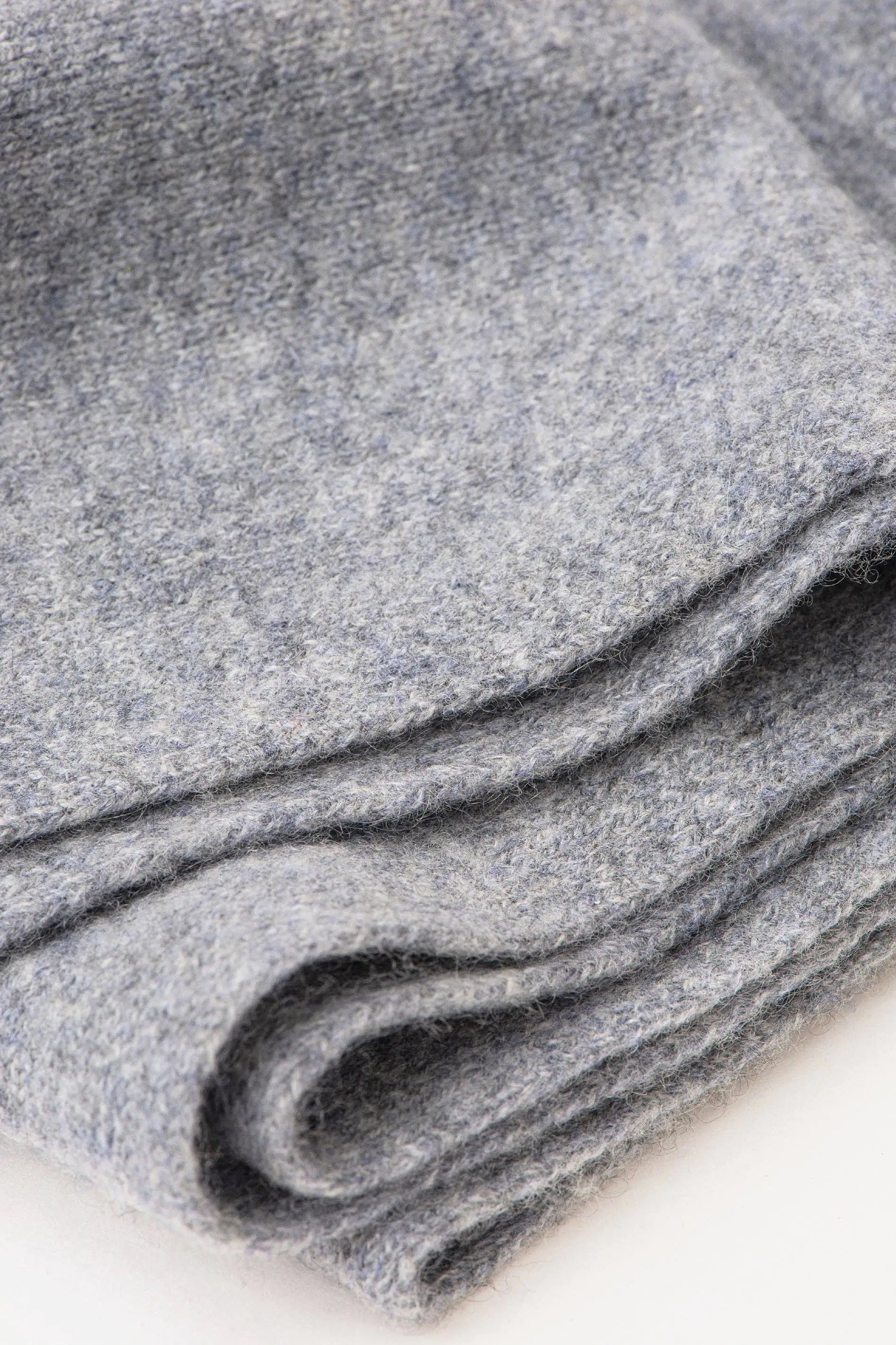 A close-up of folded gray knit fabric, showing the soft texture and heathered weave on a plain white background.