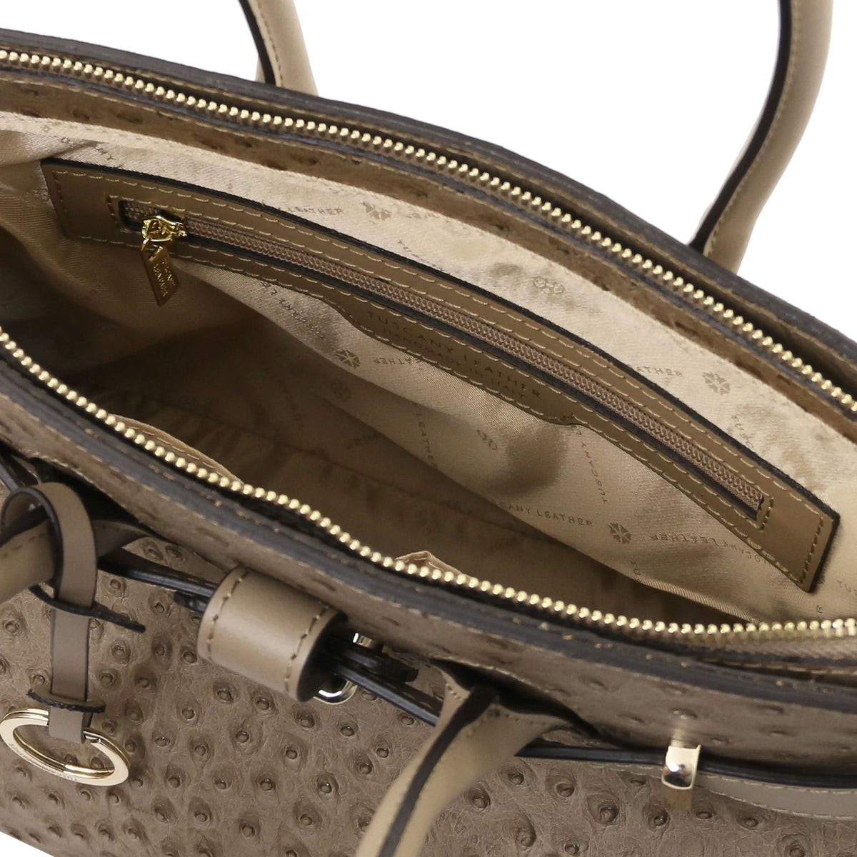 Taupe leather ostrich print handbag with interior zipper pocket and beige lining  on a white background