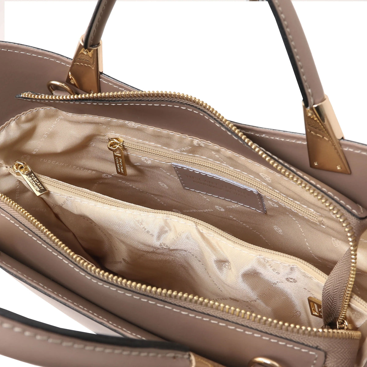 Close-up of the interior of a taupe handbag showing the beige satin-lined compartments with gold-tone zippers and hardware.