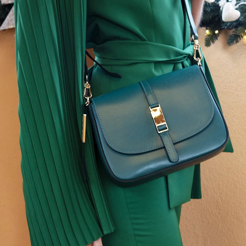 A woman wearing a green dress and a forest green cross body leather purse