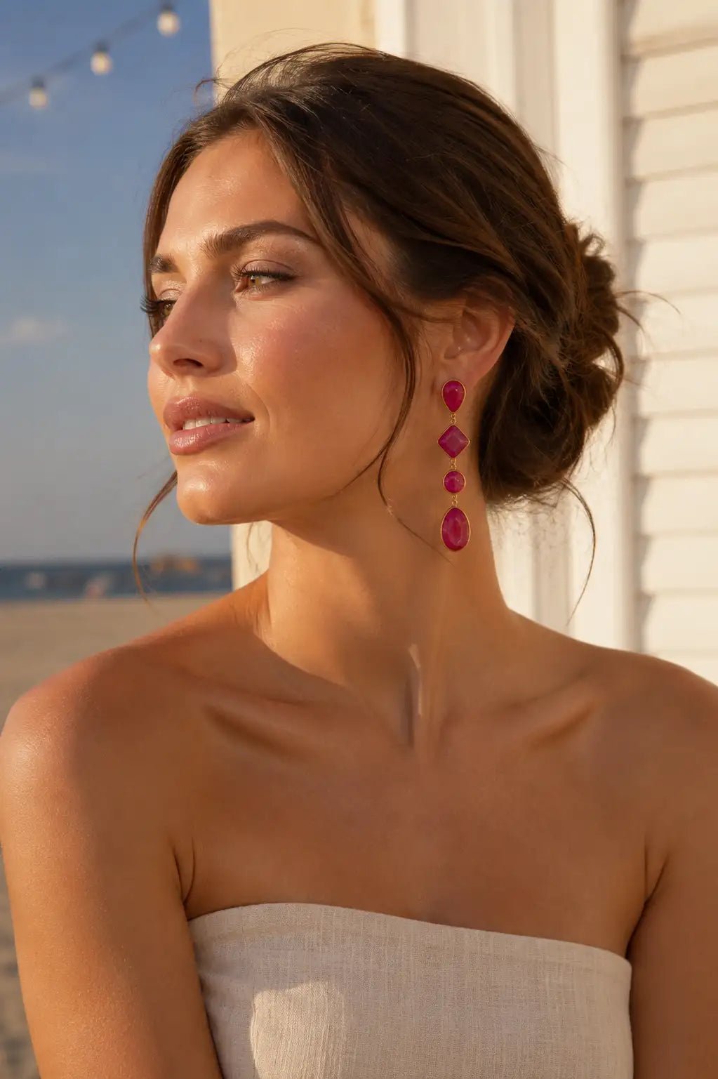 A woman wearing a linen strapless dress wearing Aaliyah Pink Jade Earrings  by the beach