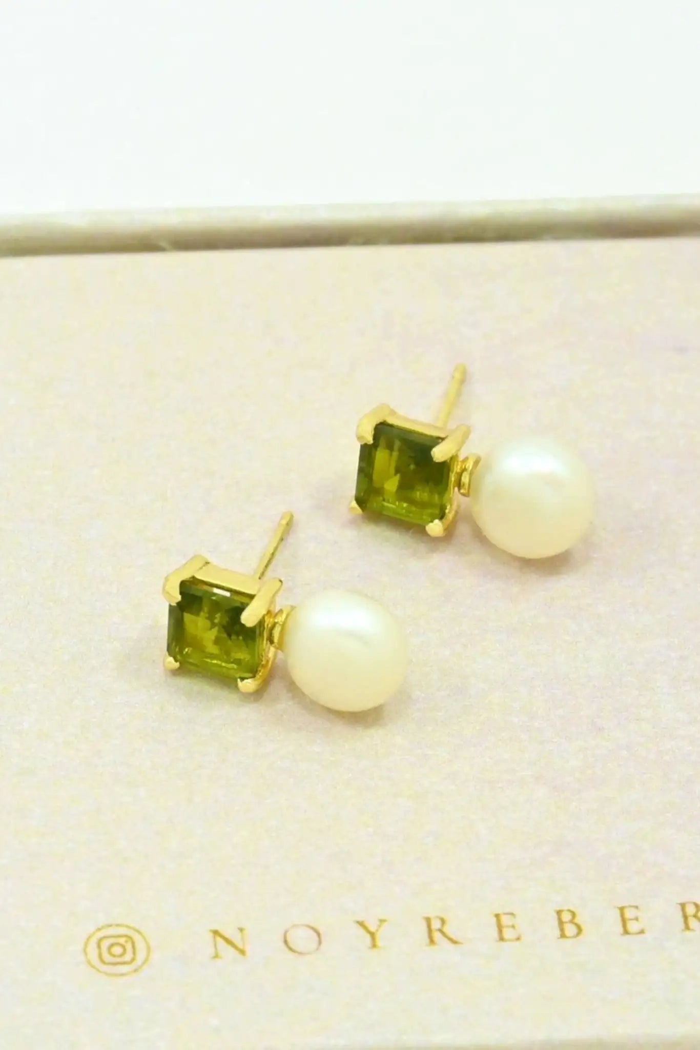 Aaliyah Stud Earrings Pearl & Green Tourmaline laying on their side on a natural hued box