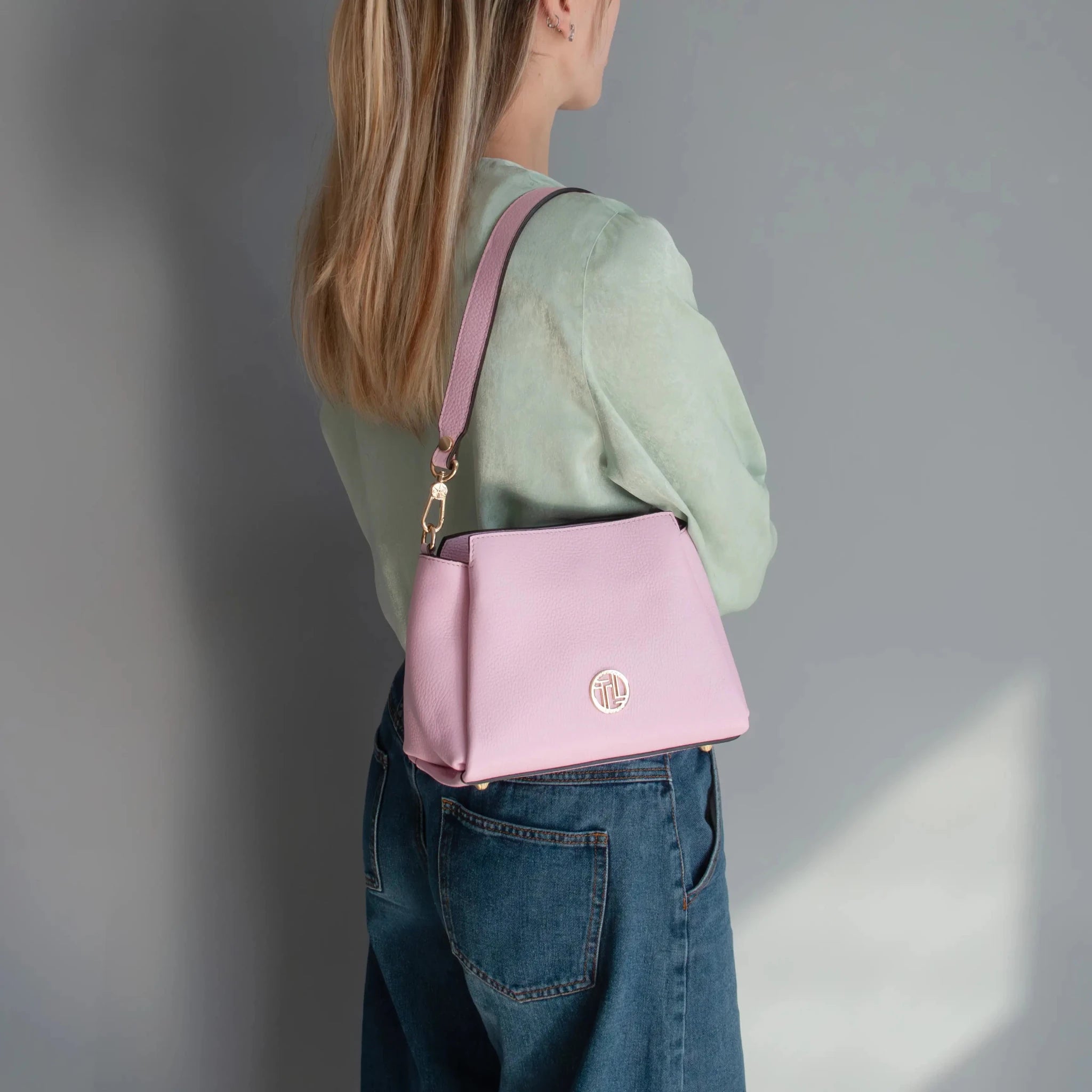Woman is holding the ballet pink Abby Leather Bag over her shoulder