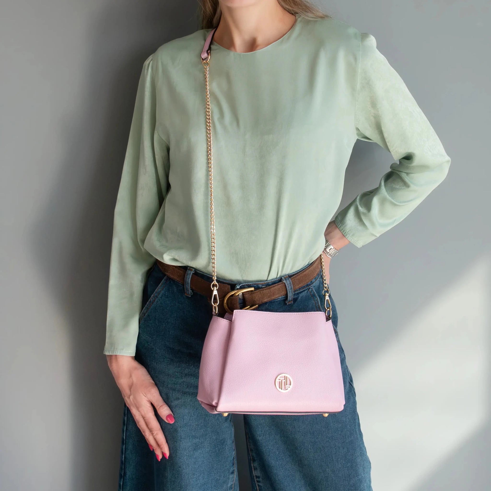 Woman is wearing the ballet pink Abby Leather Bag as a crossbody