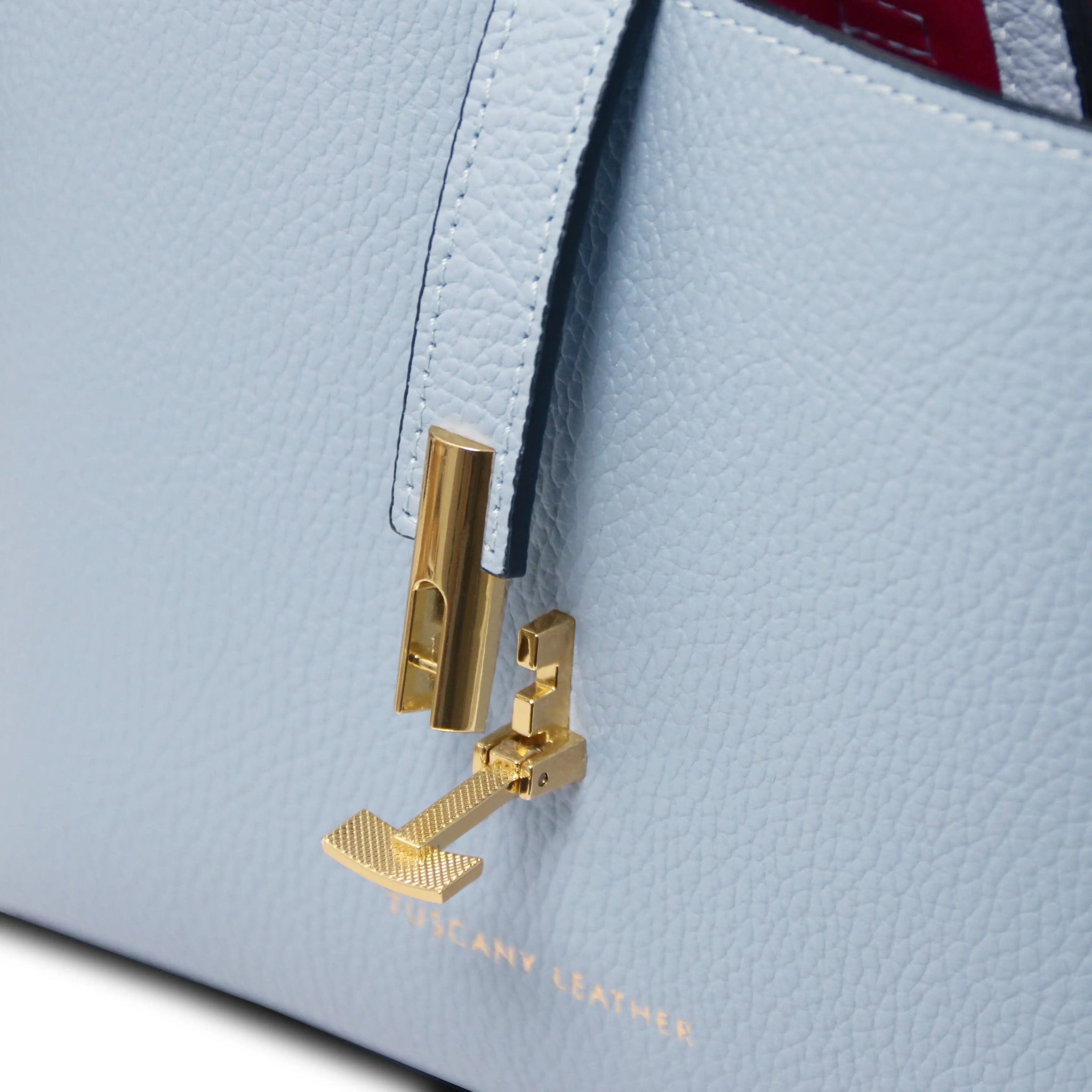 Close-up of a light blue leather handbag with gold twist lock hardware, featuring the brand name.