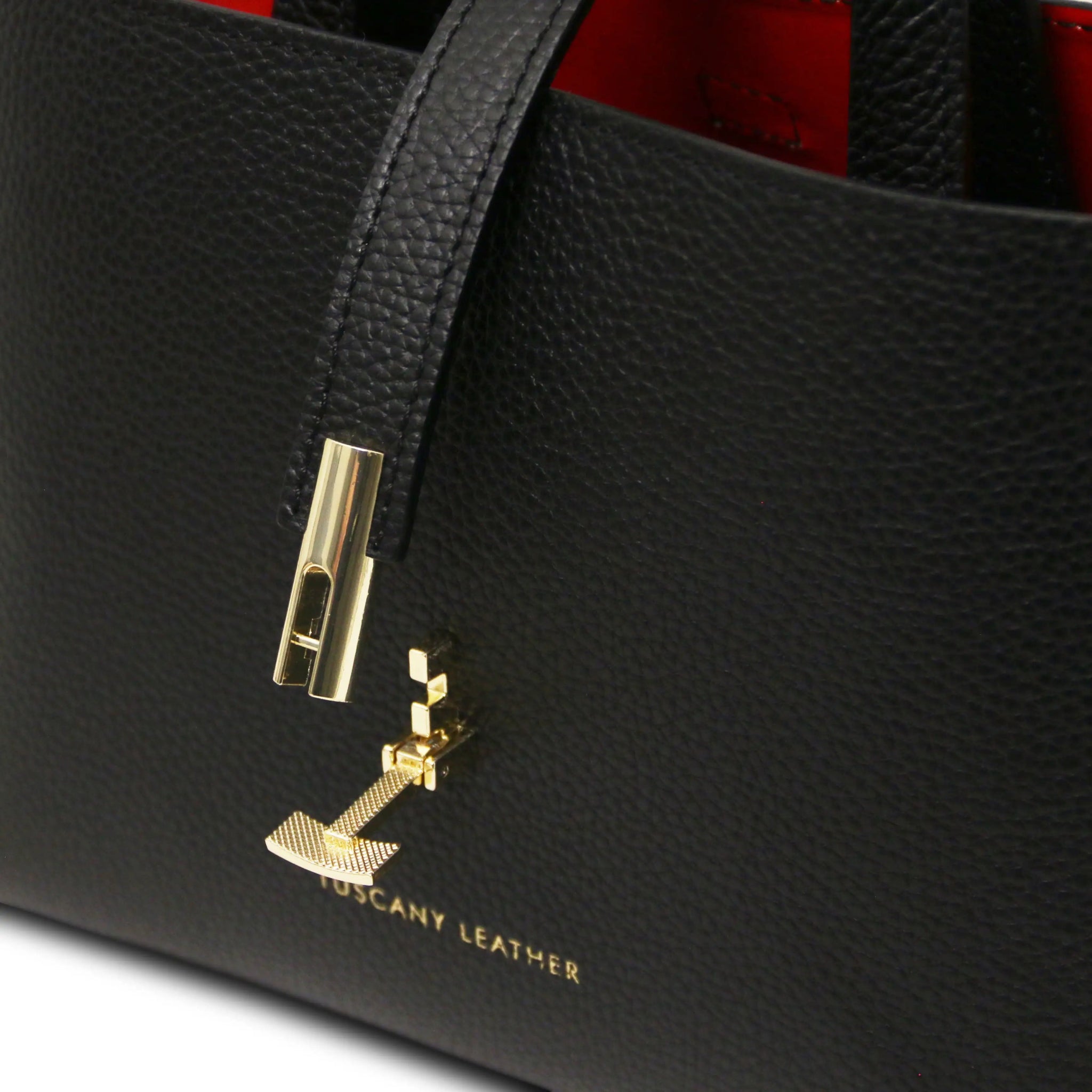 Black leather handbag with gold twist clasp lock and 'Tuscany Leather' branding.