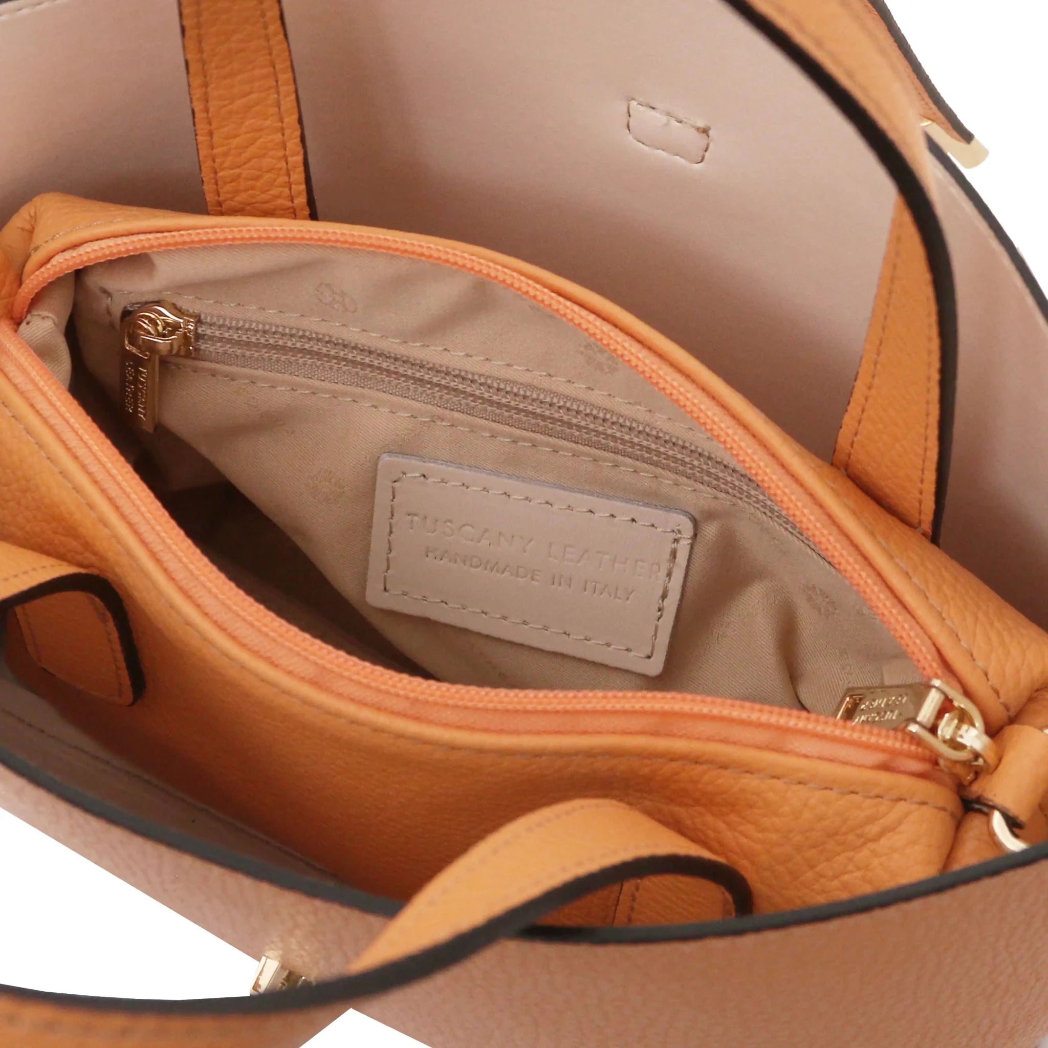 Close-up of a beige interior of apricot bag with  zip pocket and stitching details.