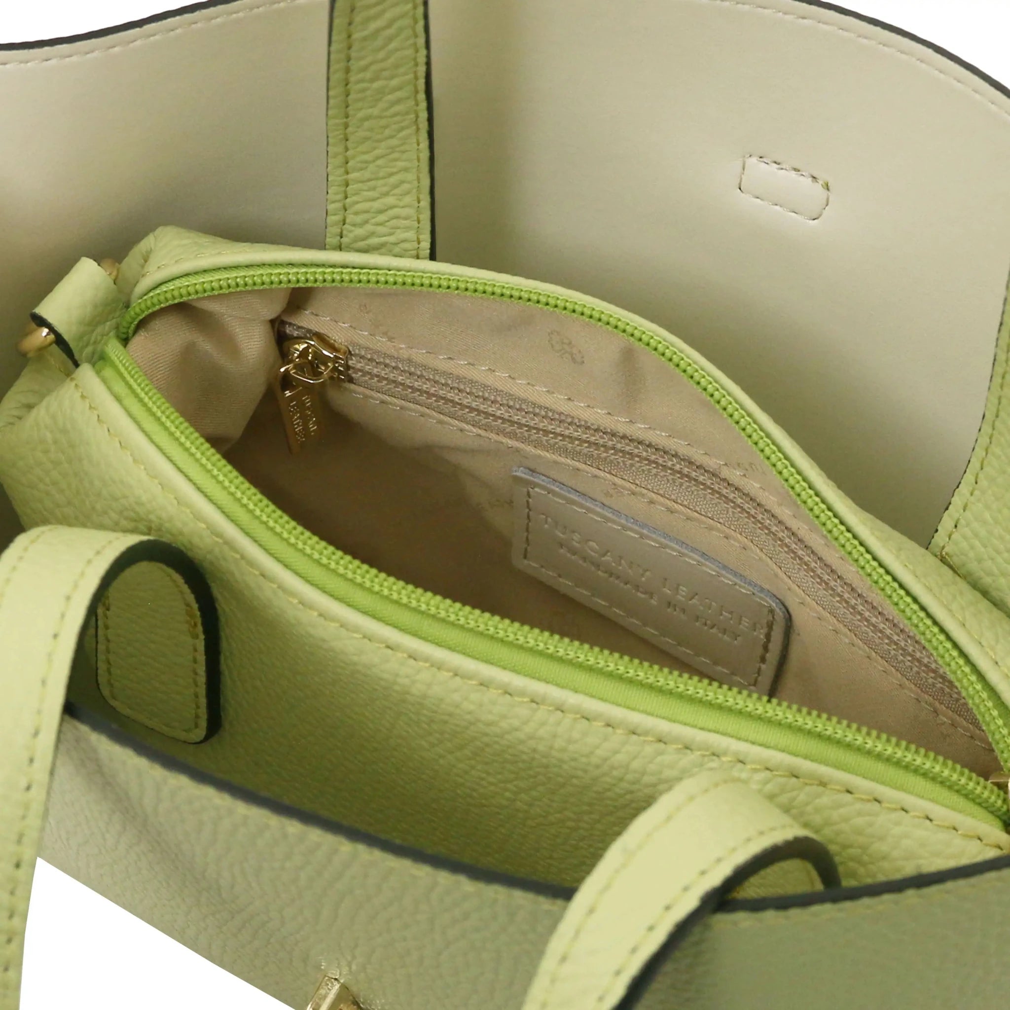 Close-up of a beige interior of lime green bag with zip pocket and stitching details.
