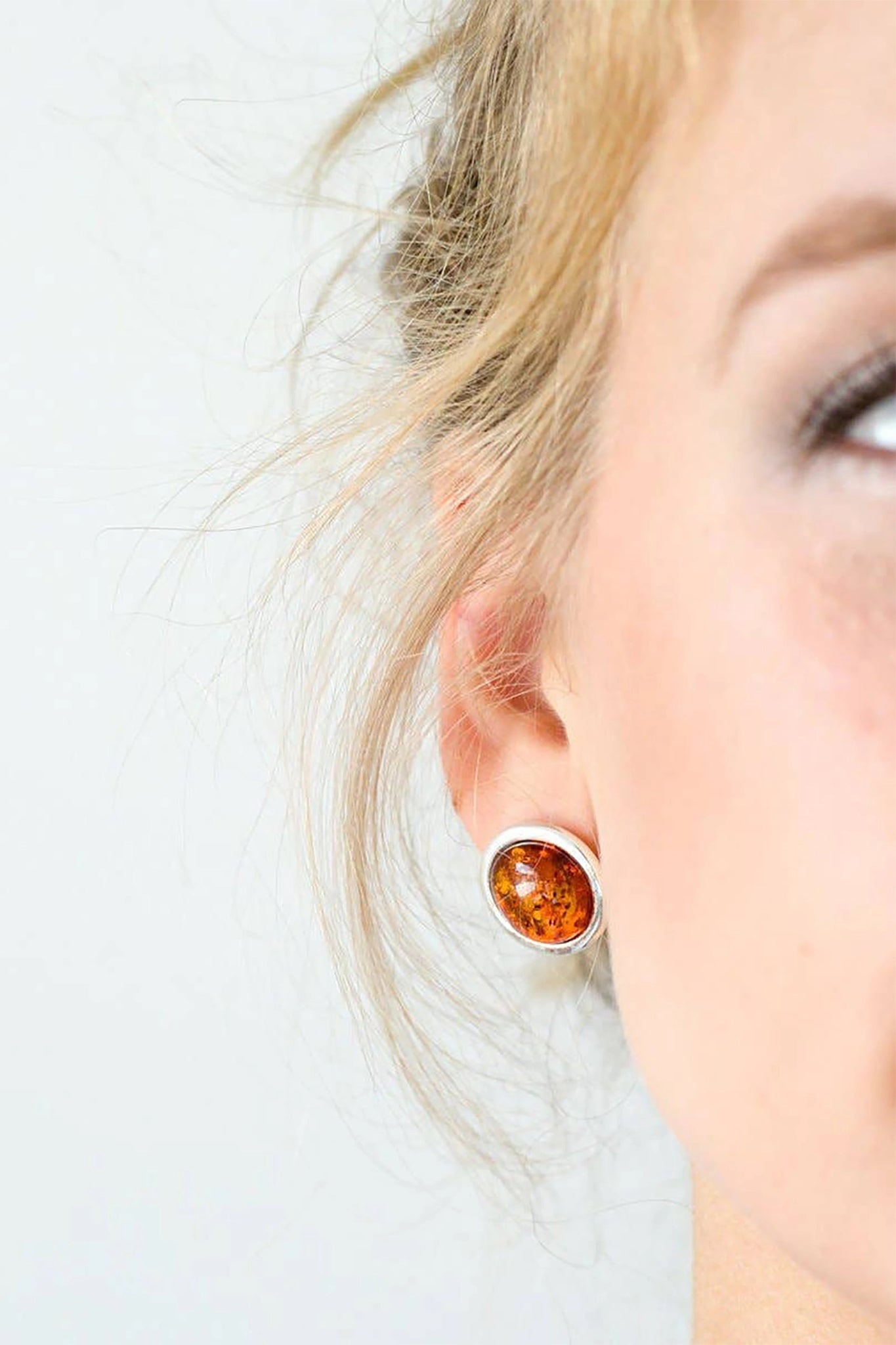 A model is wearing the Baltic Honey Amber Statement Round Stud Earrings 