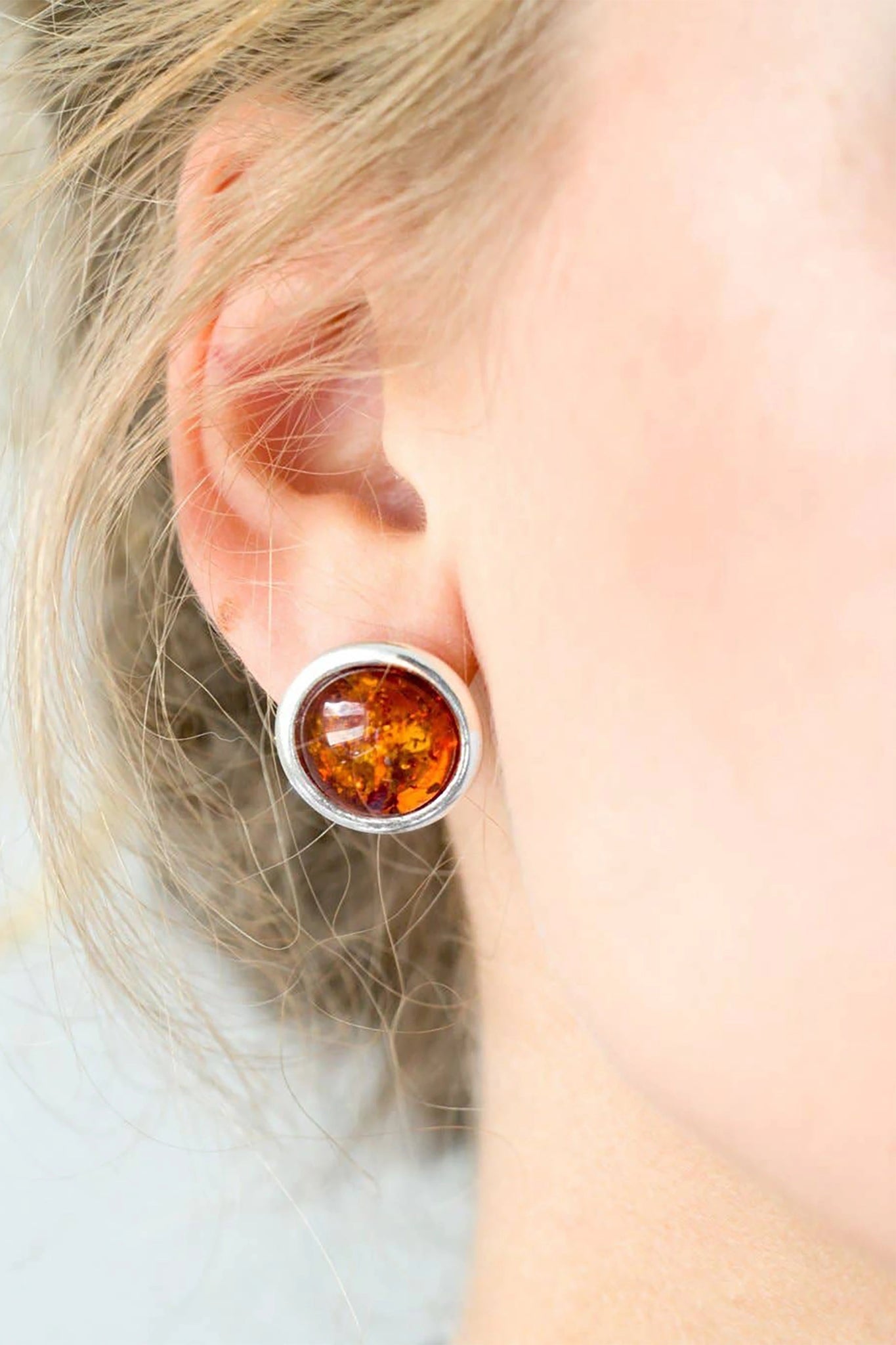 A model is wearing the Baltic Honey Amber Statement Round Stud Earrings 