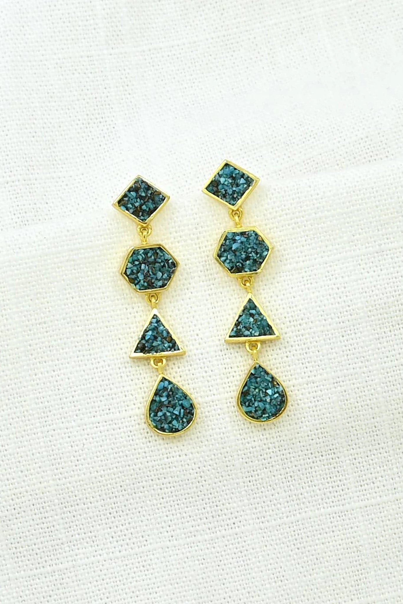 Gold and turquiose earrings on a linen background