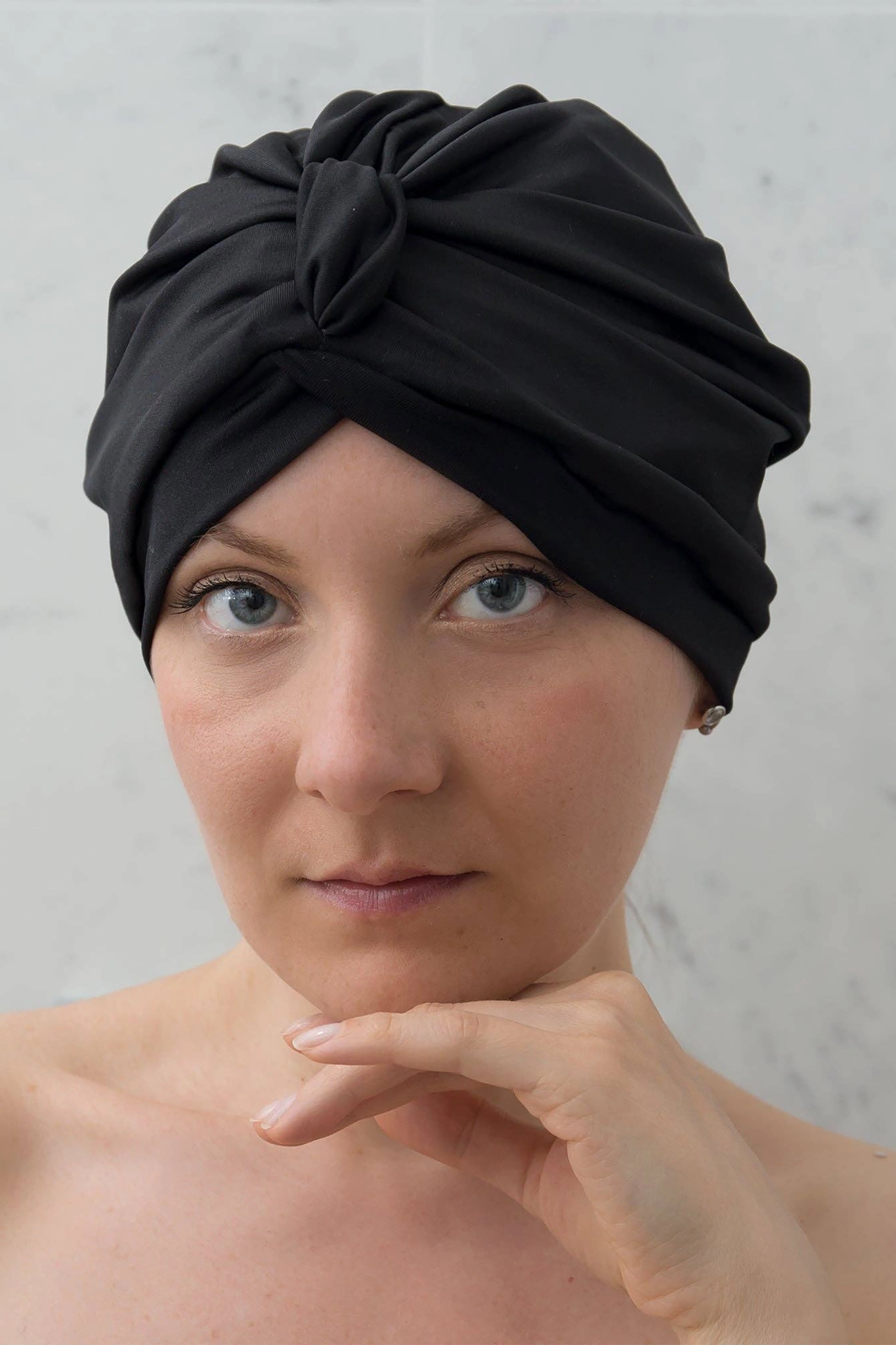 Woman wearing a black turban against a gray background