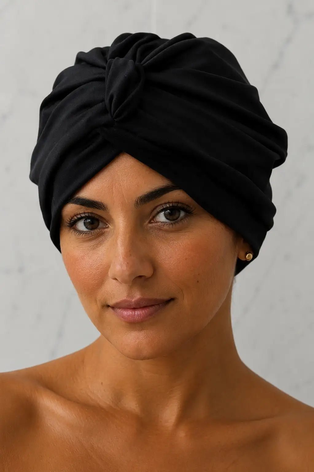 Woman wearing a black turban against a white background