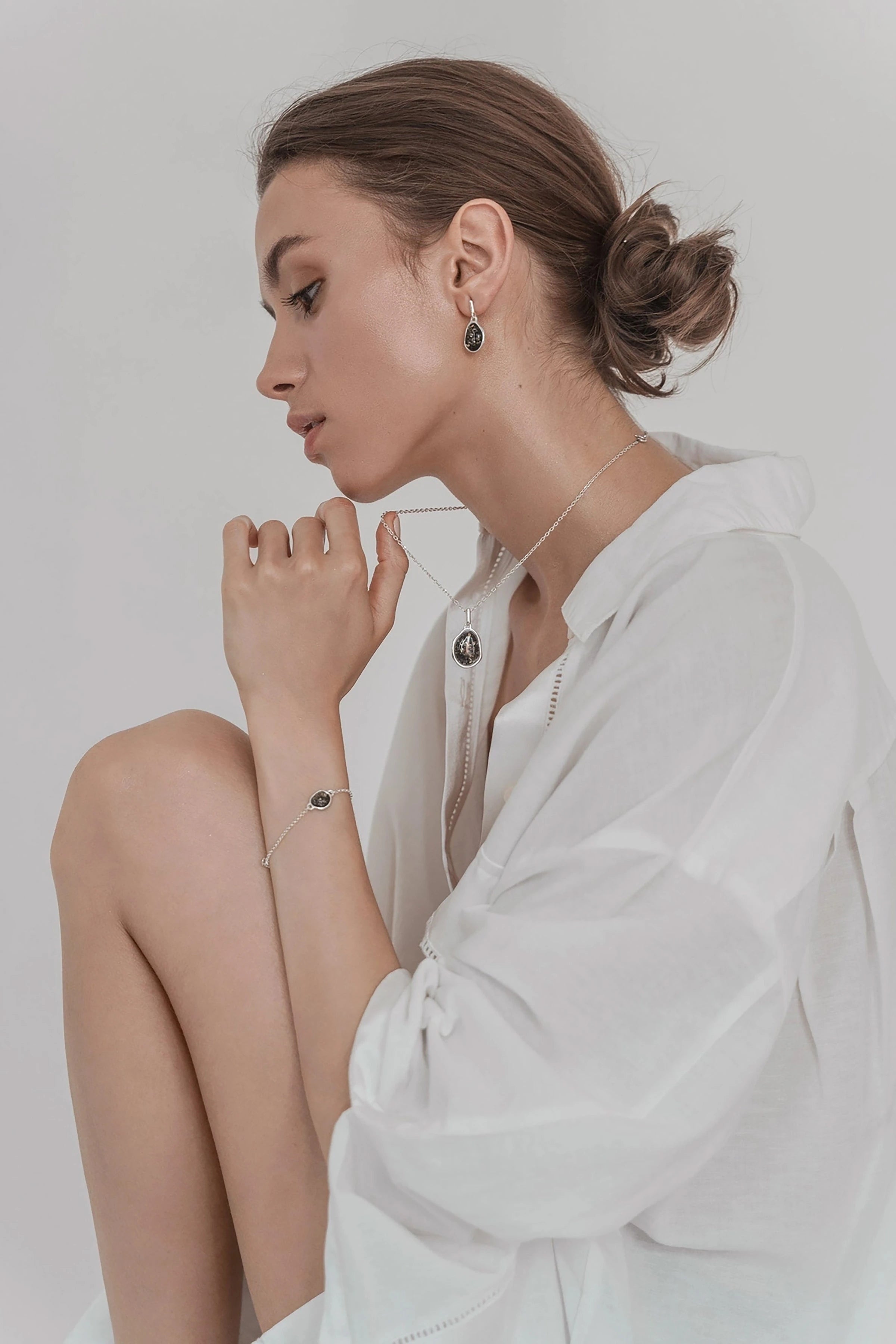 Women wearing a white blouse with the green amber asymmetrical silver necklace and drop earrings.