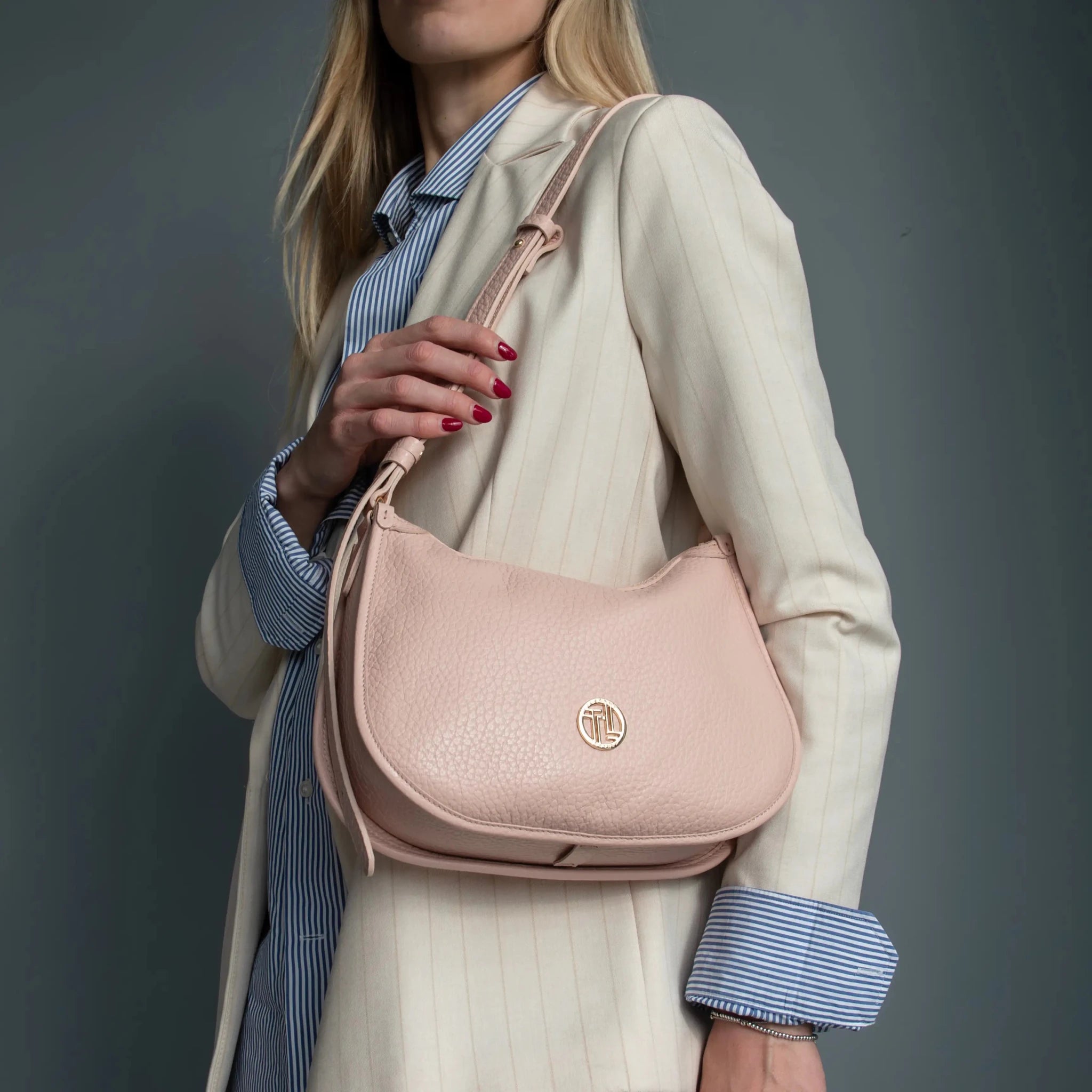 Woman wearing white suit carrying the Hoblò Handbag Nude on her shoulder