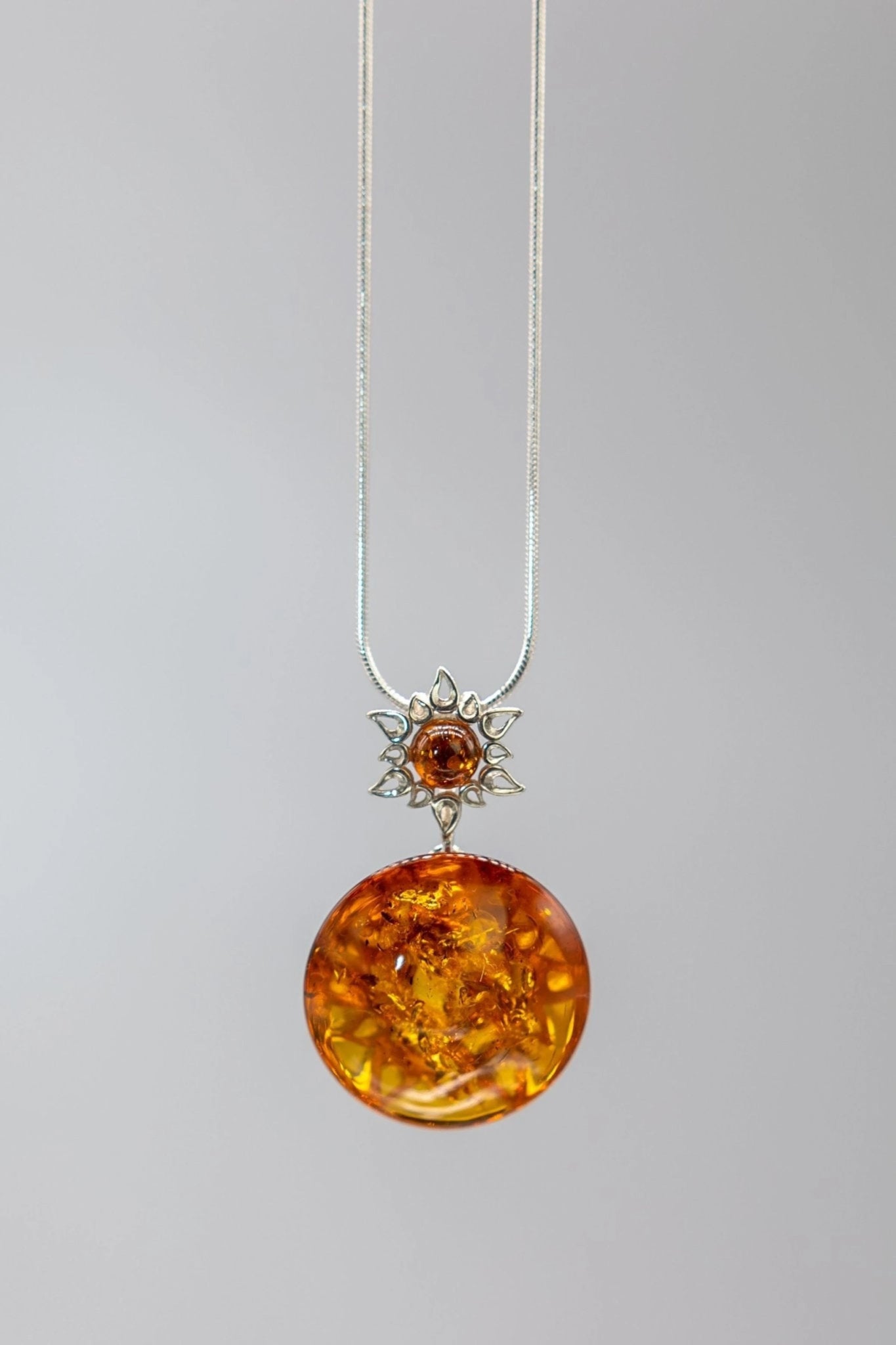 Honey Amber Star Necklace hanging on a gray background