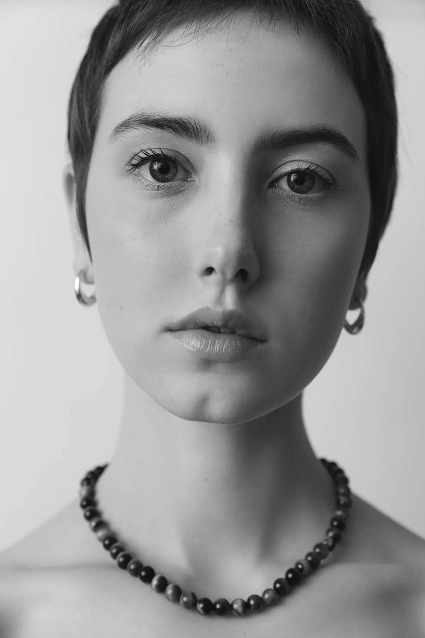 A black and white image of a female model wearing the Inez Sterling Silver Hoop Earrings