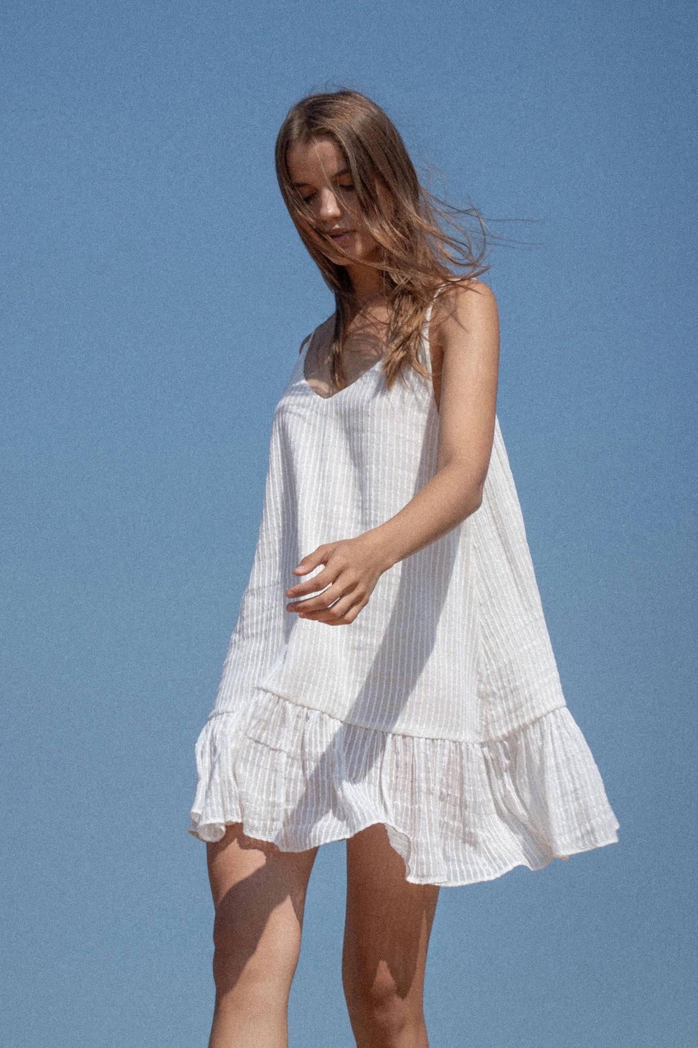 Woman wearing a white dress against a clear blue sky