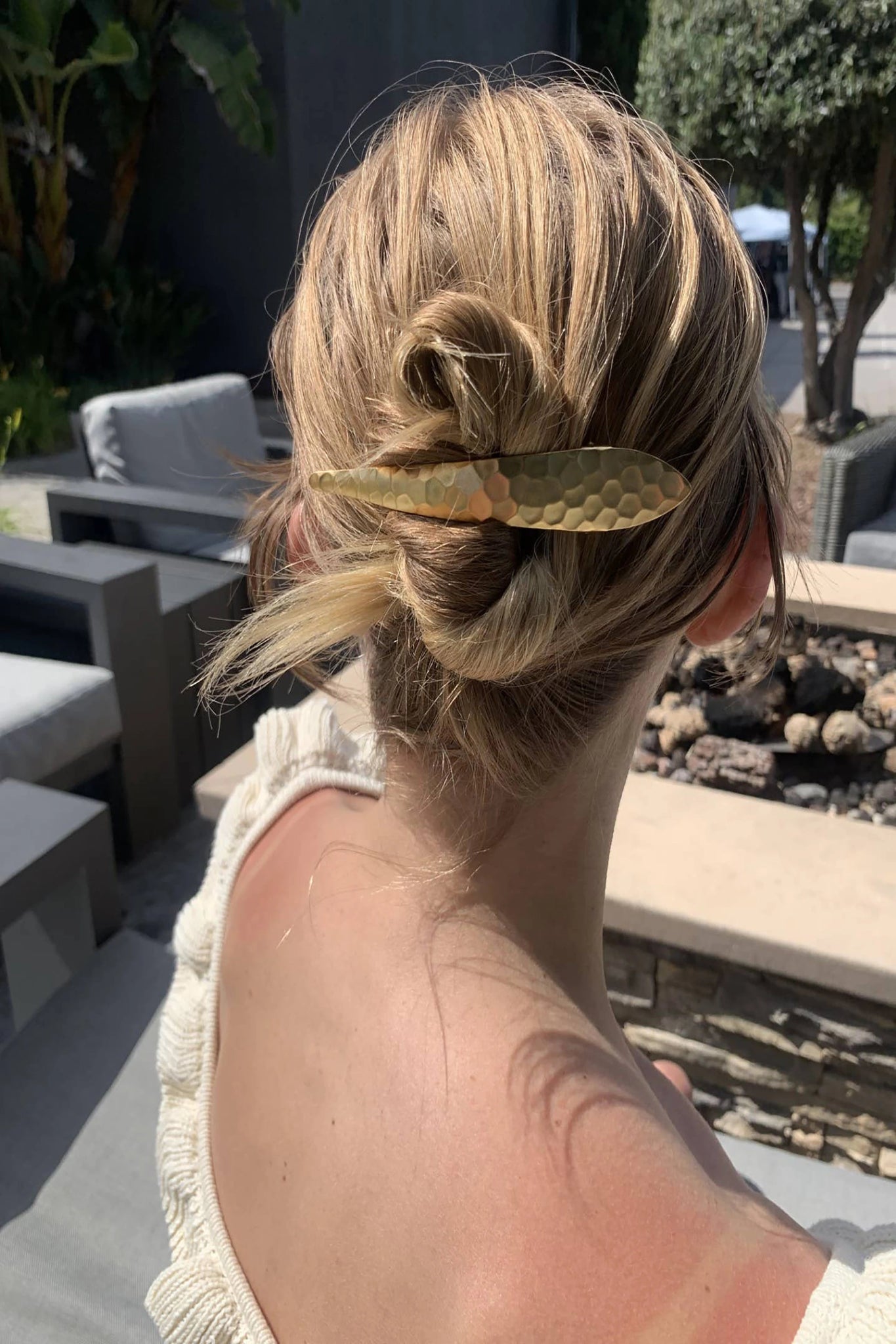 A woman wearing the Hammered Gold Hair Clip outdoors