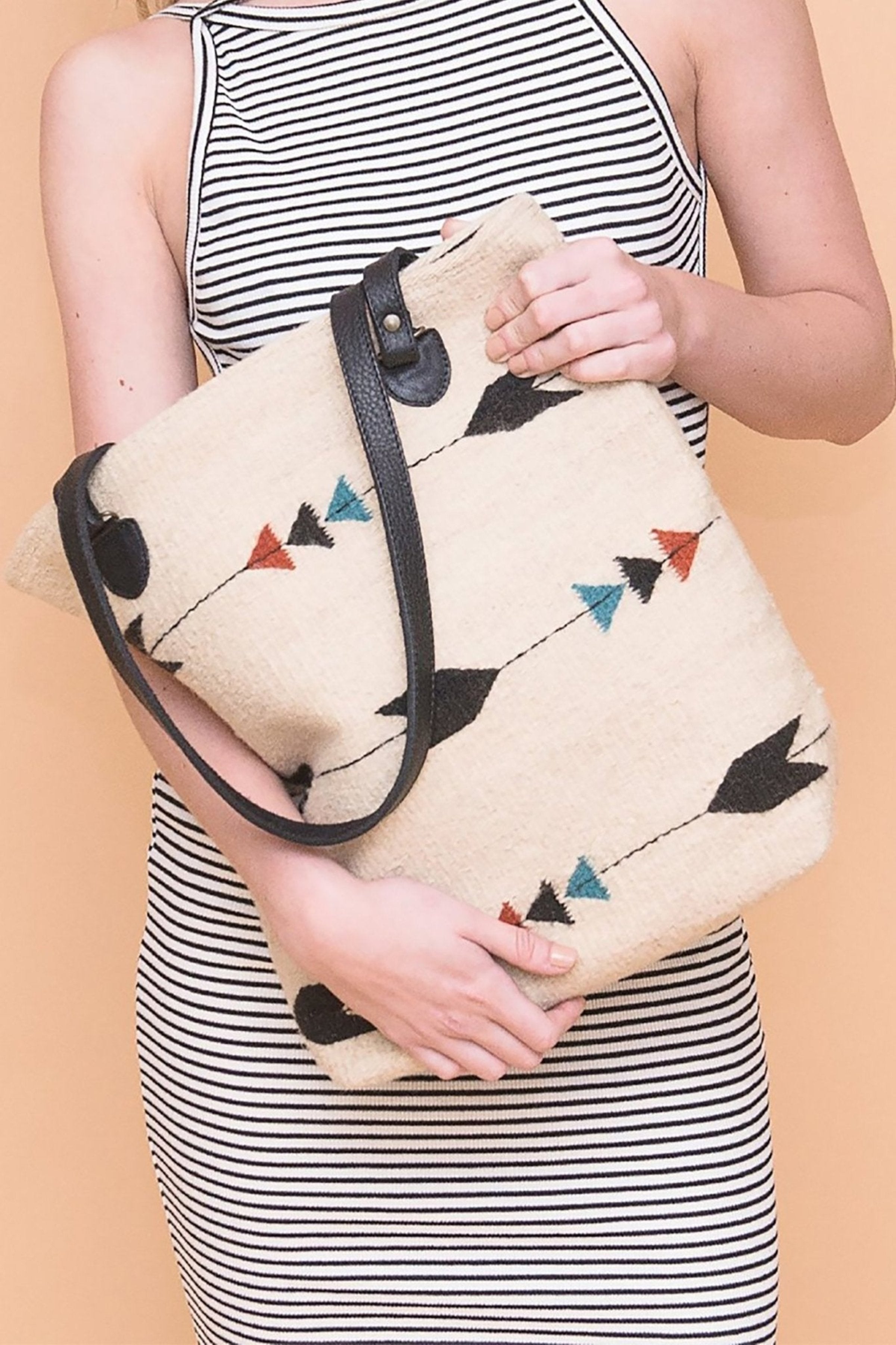 Obsidian Arrow Tote Bag is held by a female model wearing a blue and white striped sleeveless dress - L'Atelier Global