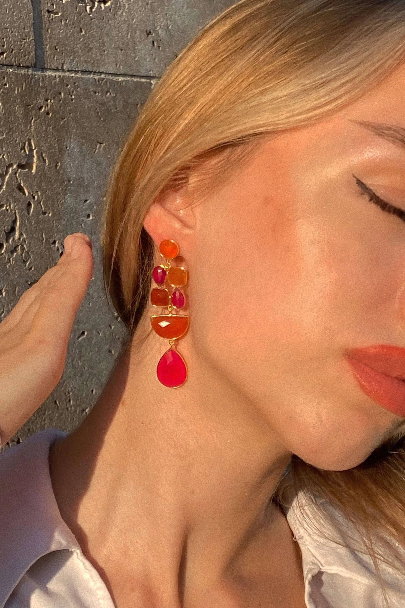 Close-up of a woman wearing colorful earrings in pink and orange gemstones