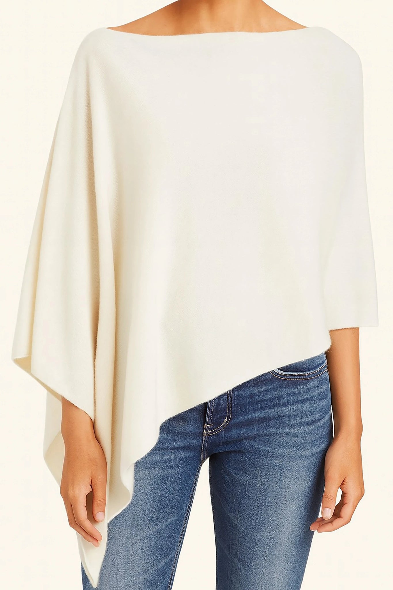 A model wearing the Ravello Cashmere Poncho in ivory on blue jeans