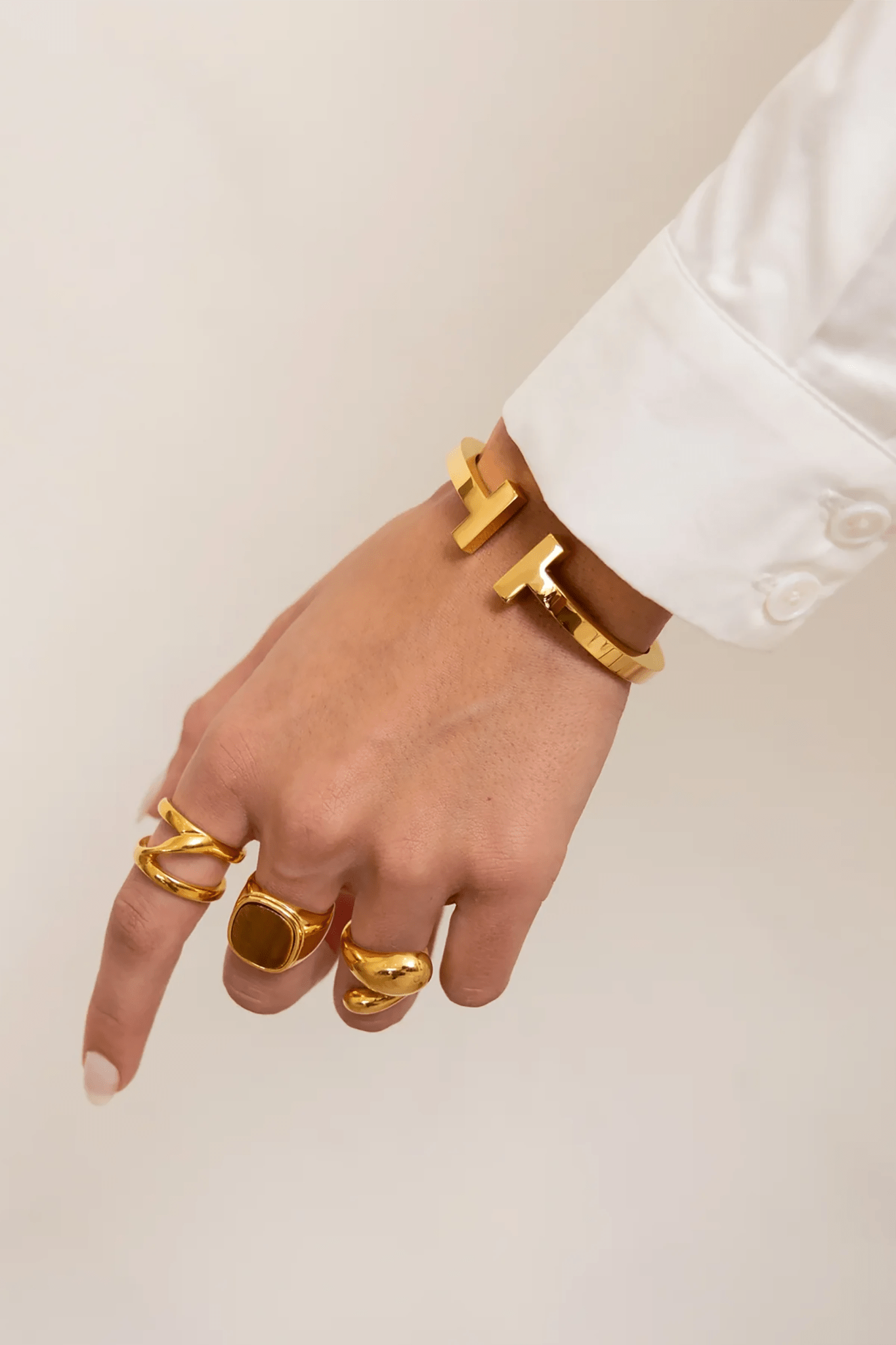 Sadie Hinged 18K Gold Bracelet on a model's left wrist showih her hand with god rings on each finger 