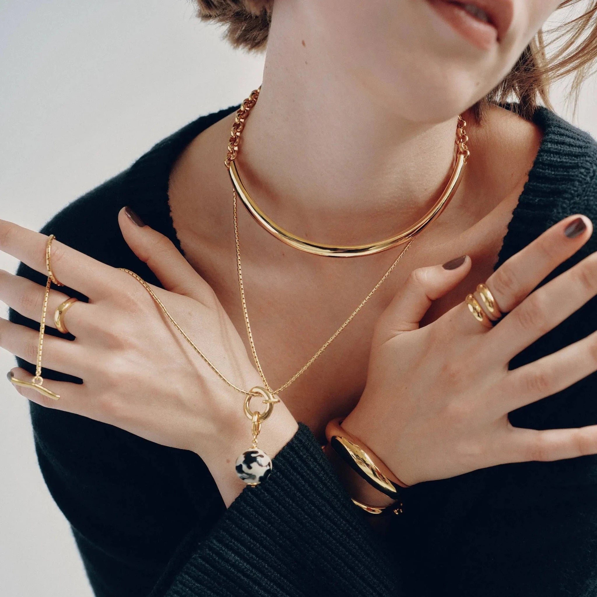 Close up front view of Golden Arc Collar Necklace on a woman's wearing all gold jewelry
