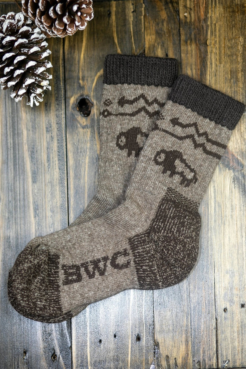 The American Bison Wool Crew Sock on wood, snowy pinecone on top left corner 