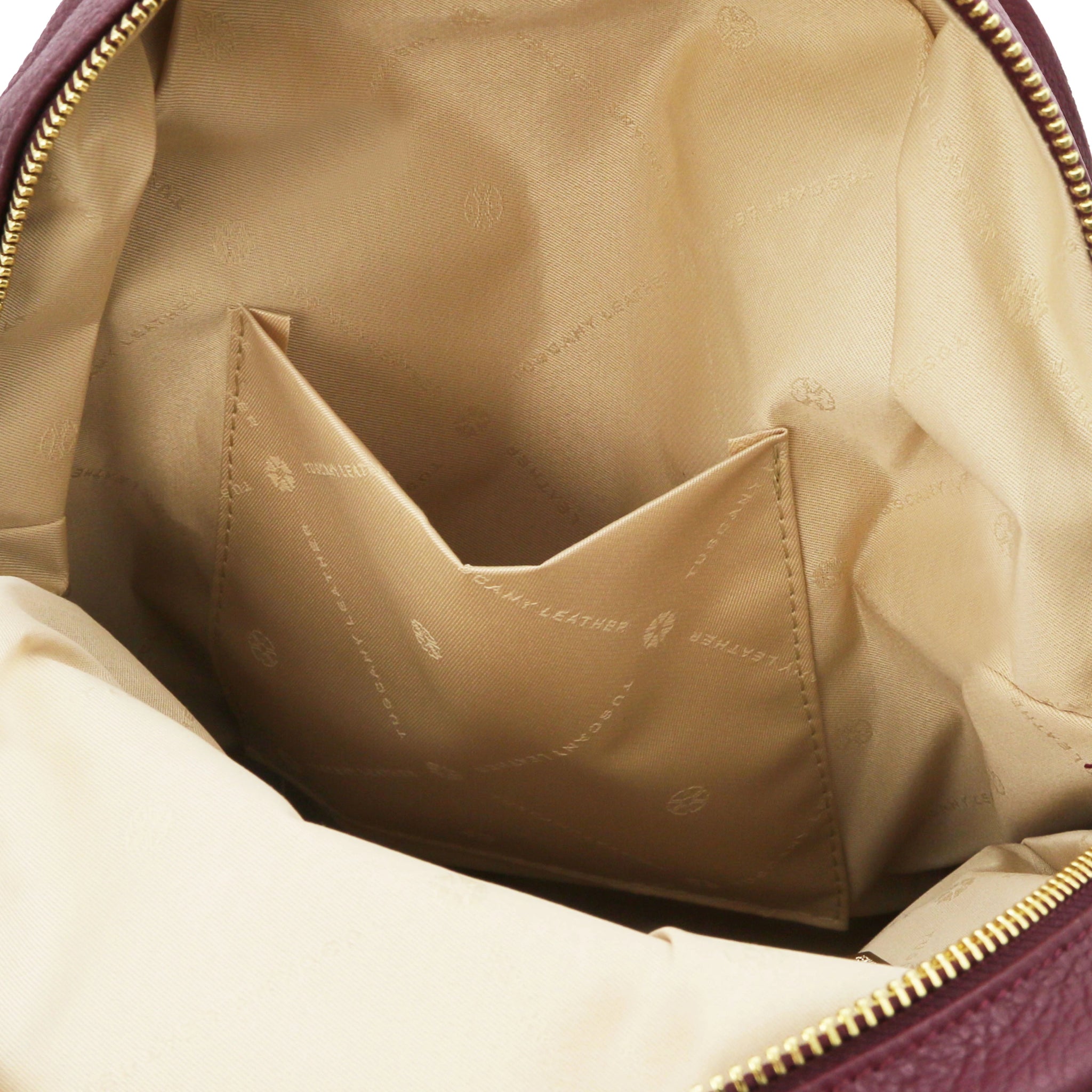 Interior open pocket with beige lining view of Bordeaux backpack with gold zipper