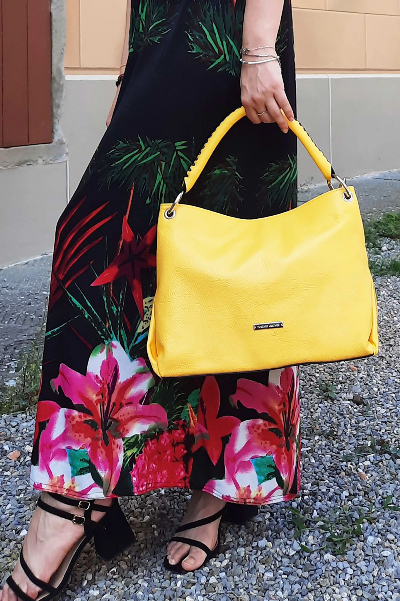 A female model wearing black floral skirt and top holding the TL Bag Soft Leather Handbag in Yellow - L'Atelier Global