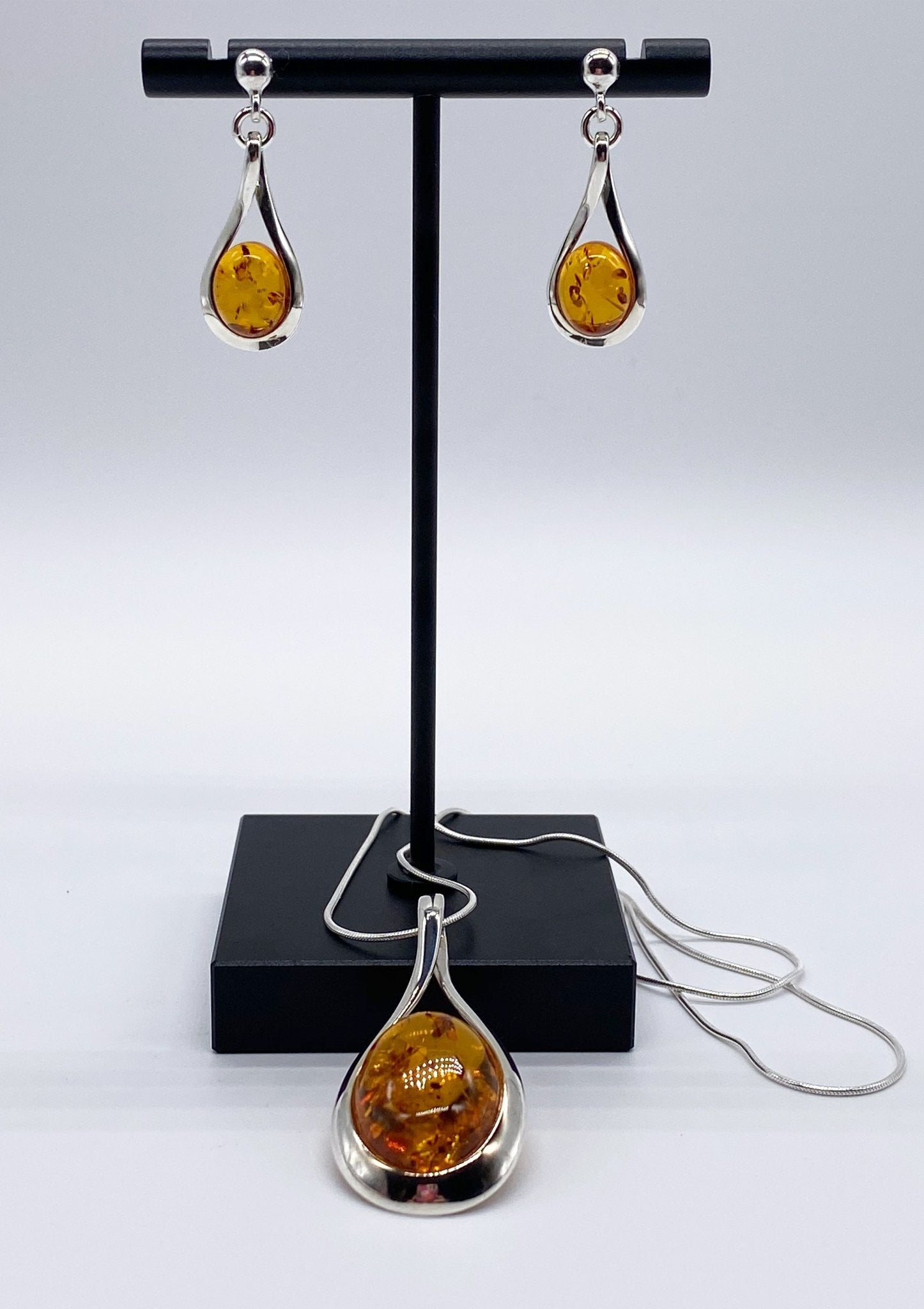 Baltic Honey Amber Sculptured Tear Drop Necklace and matching earrings on a jewelry display - L'Atelier Global