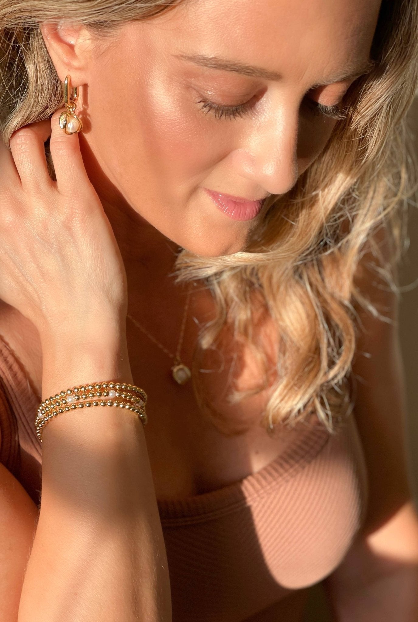 Set of 3 golden beaded bracelets with pearls on a model's right arm 