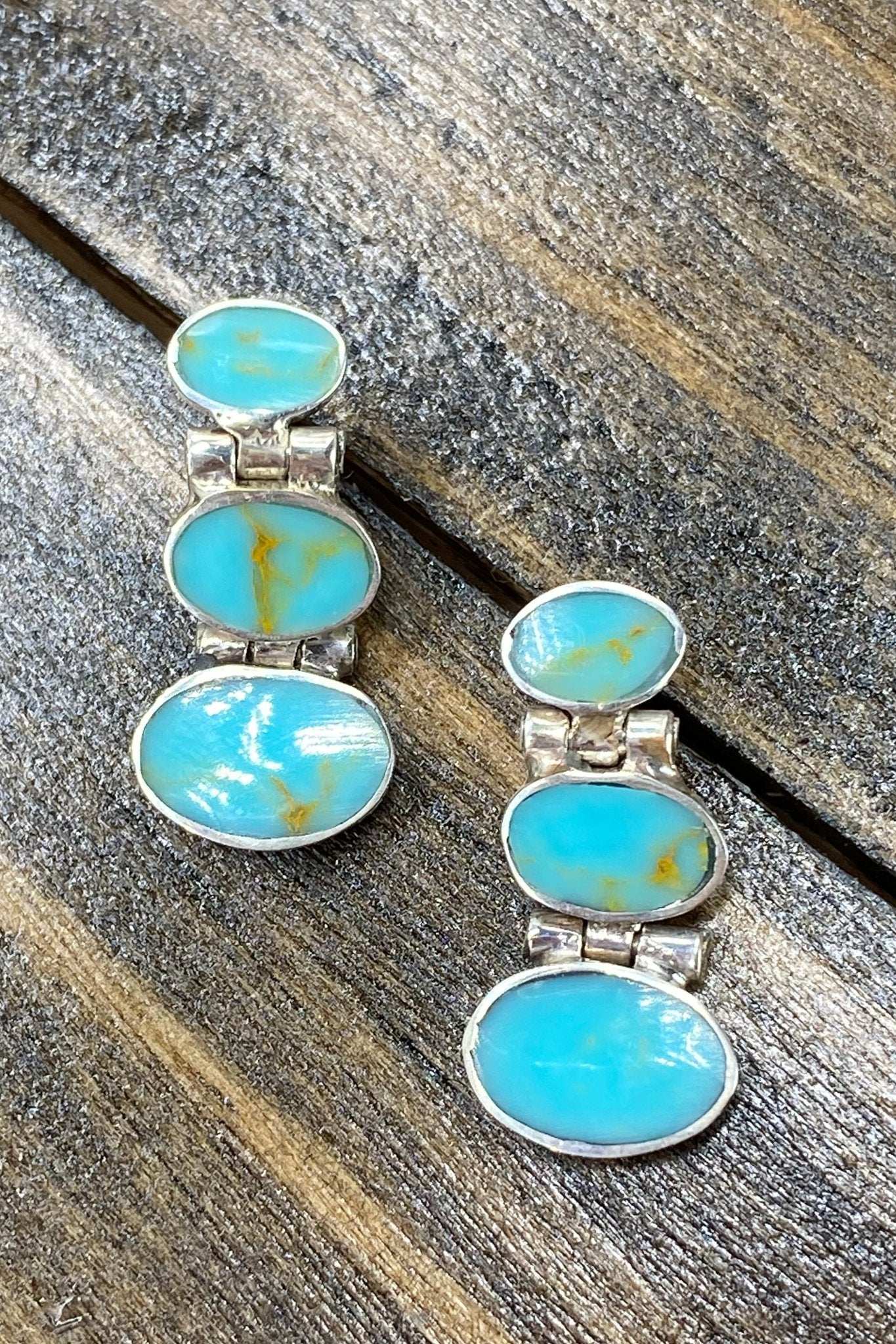 Chilean Turquoise Oval Drop Earrings laying on a natural wood background - L'Atelier Global