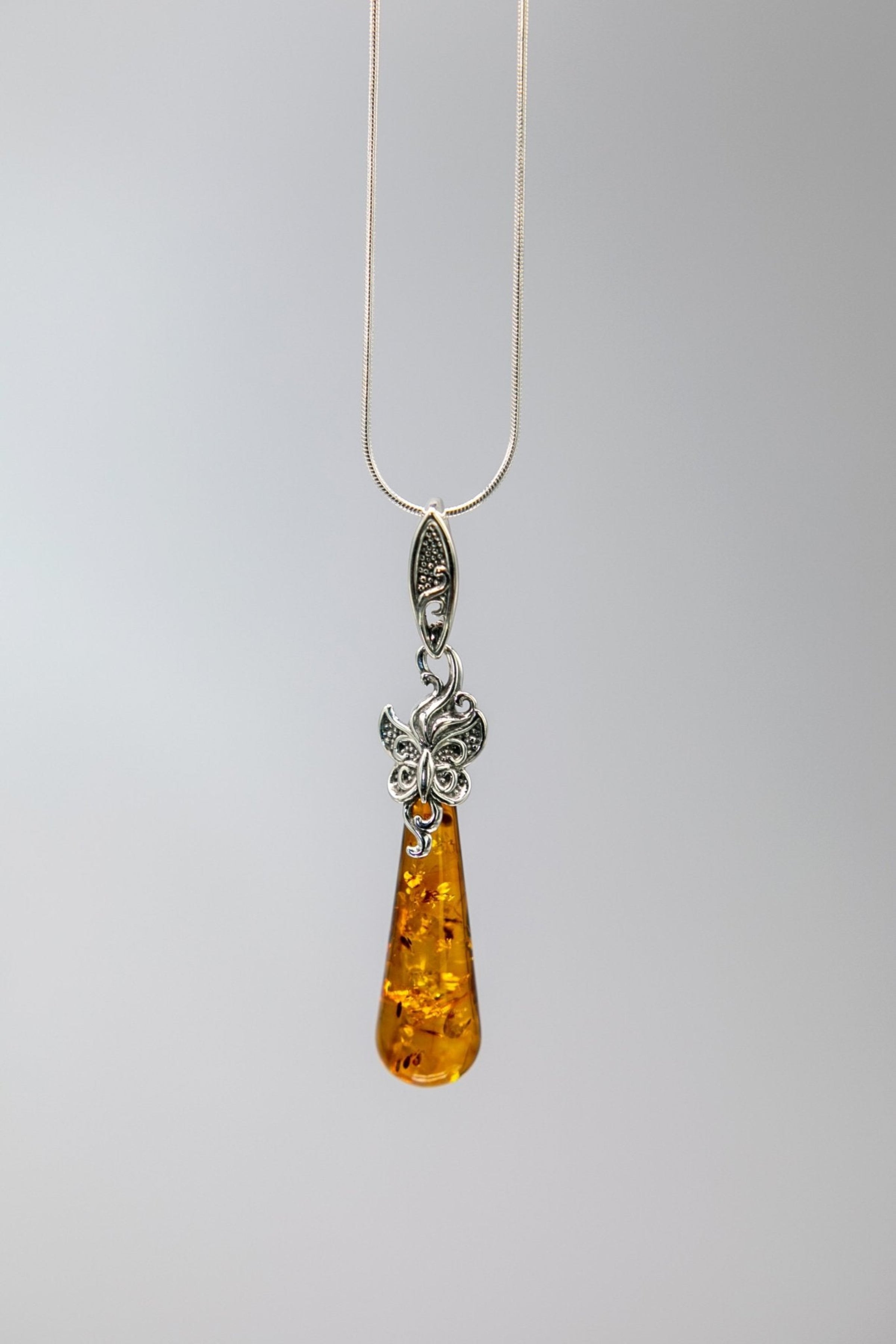 Honey Amber Butterfly Tapered Pendant Necklace hanging on a gray background - L'Atelier Global