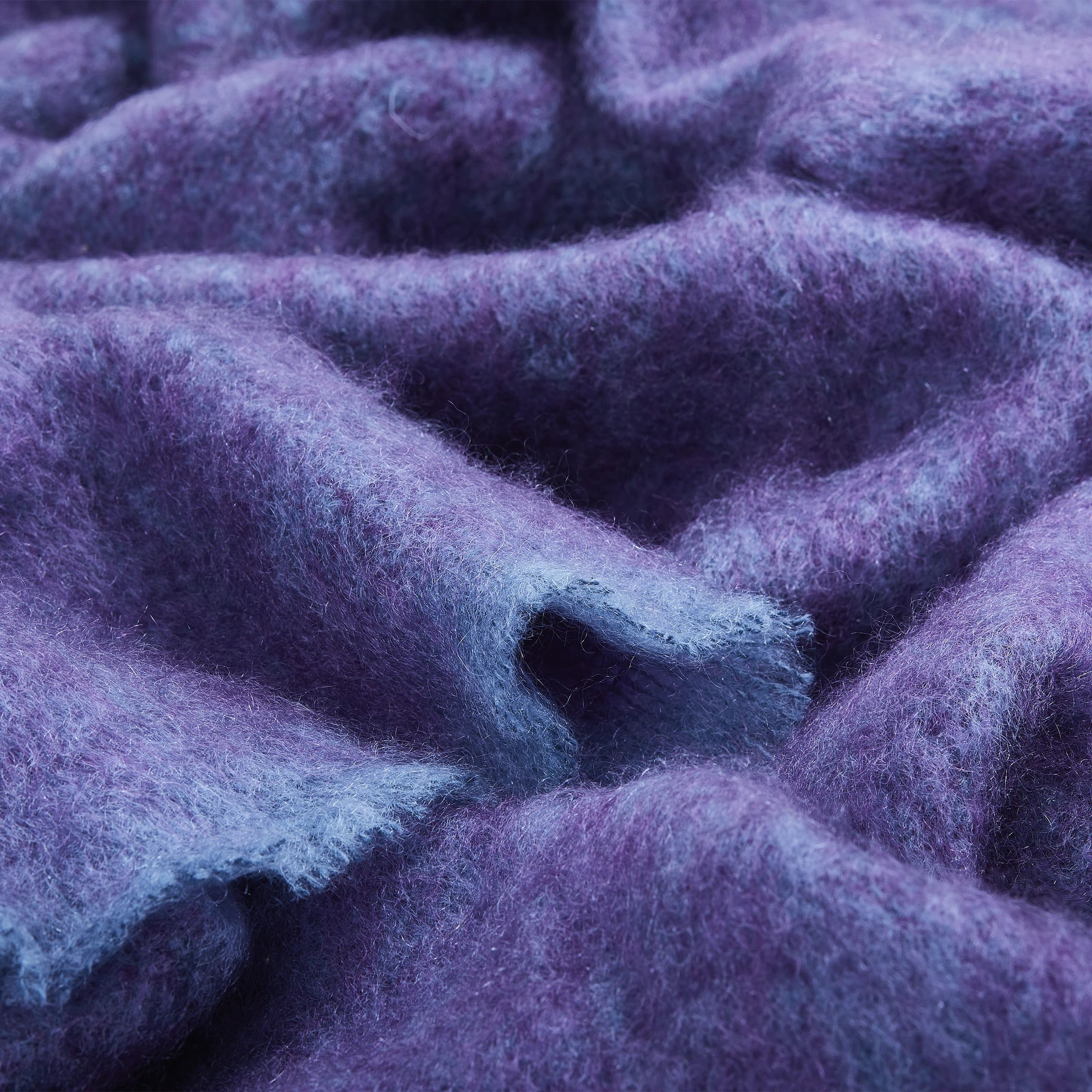 Close up of Irish Kilkenny Aubergine Melange Handloomed Plush Mohair Throw with light vibrant blue trim fabric